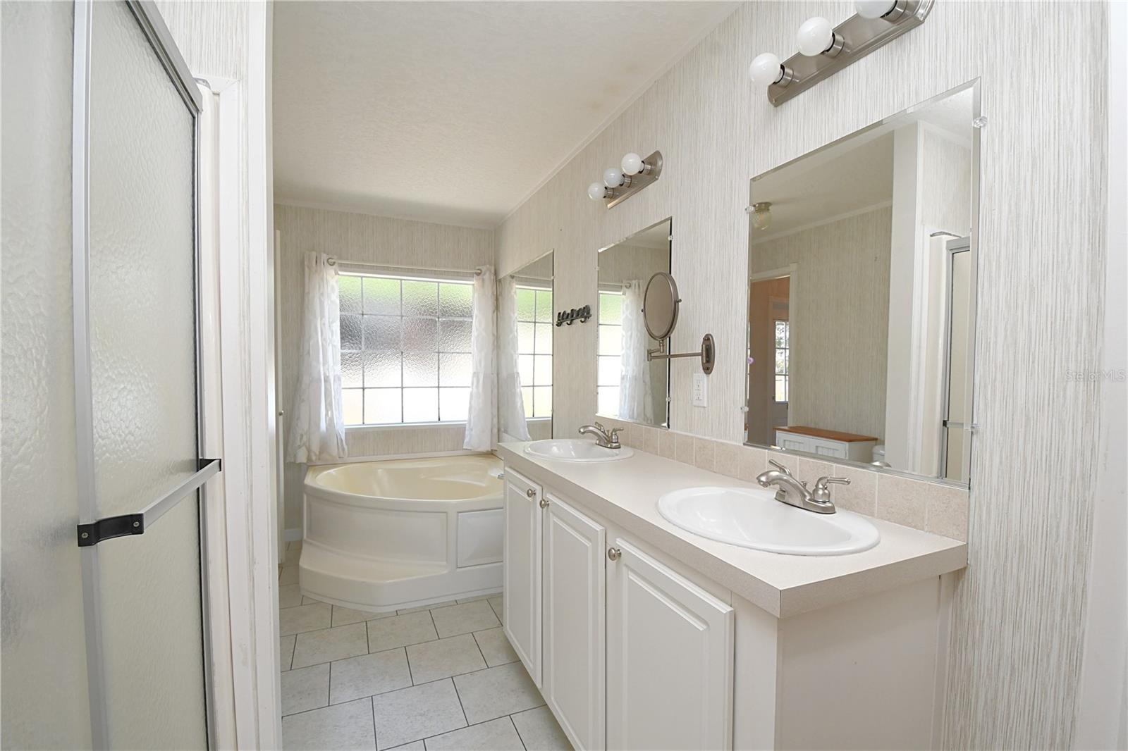 The master ensuite bathroom has a double sink mirrored vanity with lighting and storage beneath.