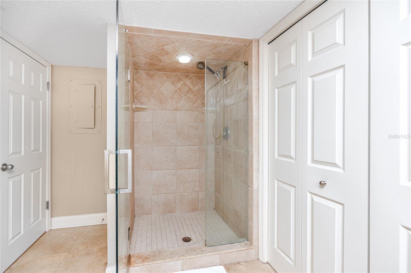Single vanity with granite countertop and walk in shower with frameless glass doors