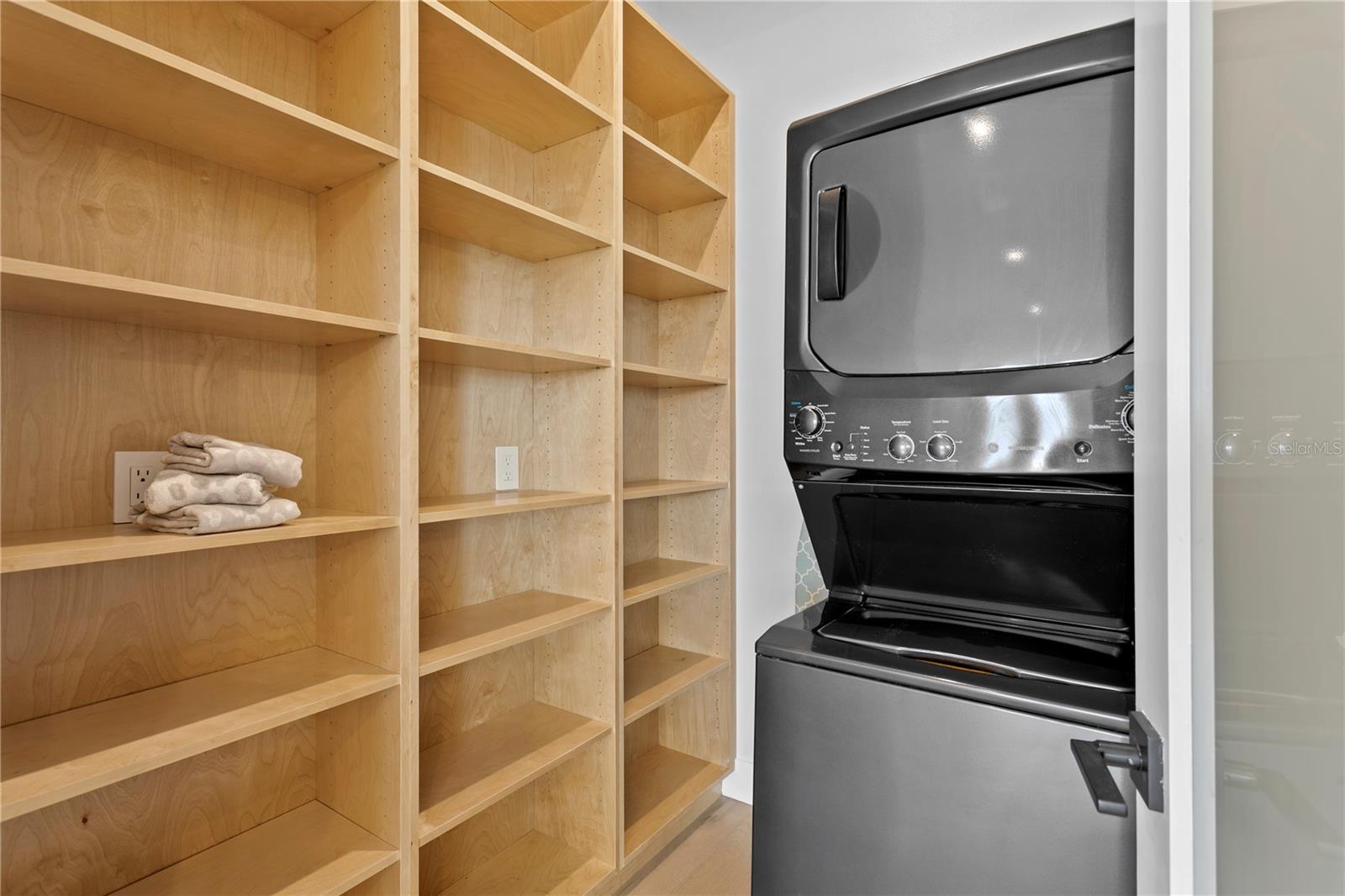 Walk in pantry with stacked washer and dryer located next to the kitchen