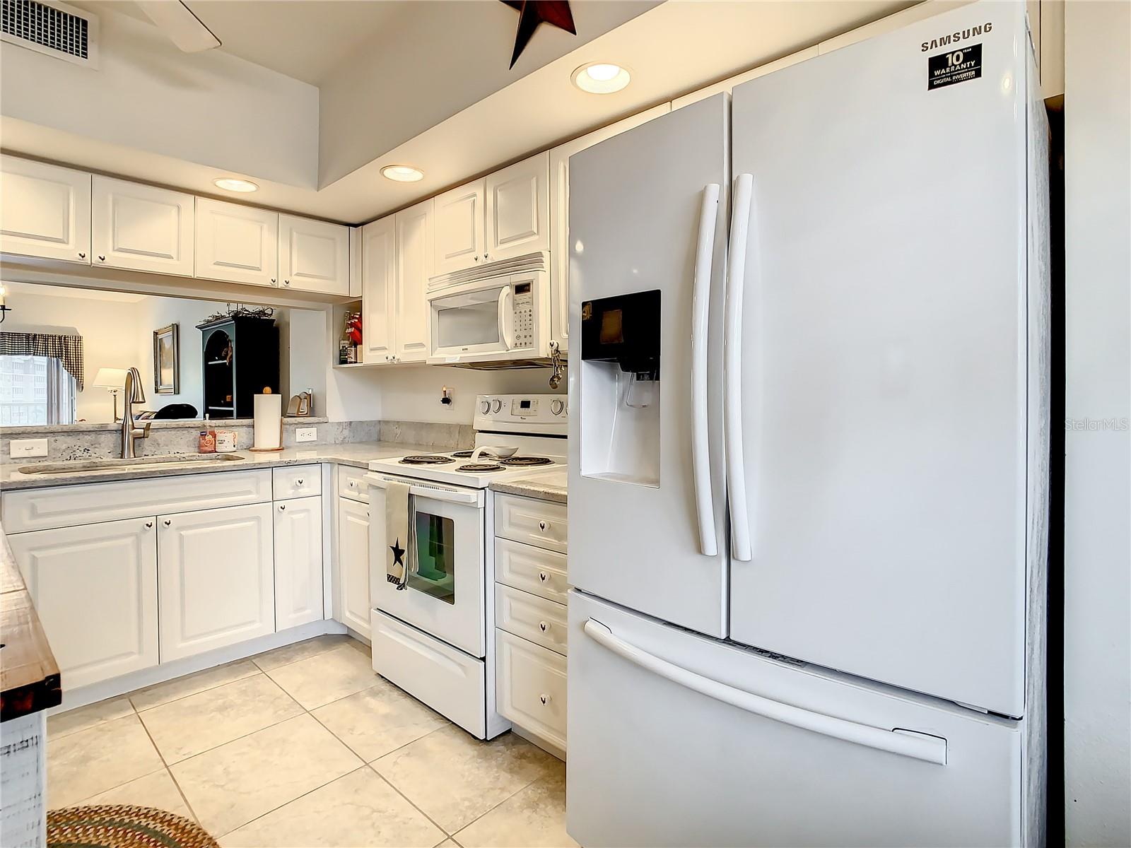 Spacious kitchen white cabinets,  updated granite countertops, and white appliances