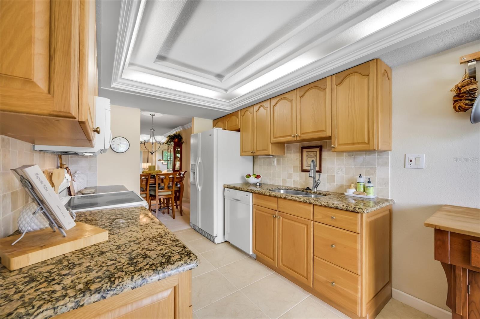 Solid wood kitchen cabinetry with granite countertops. Side by side refrigerator, dishwasher.
