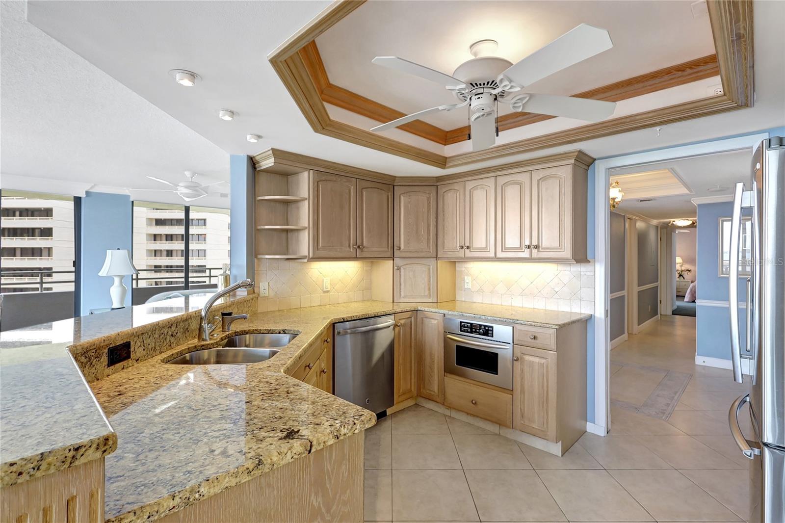 Granite counters, wood cabinetry, appliance garage, built-in wine rack, deluxe coffered ceiling