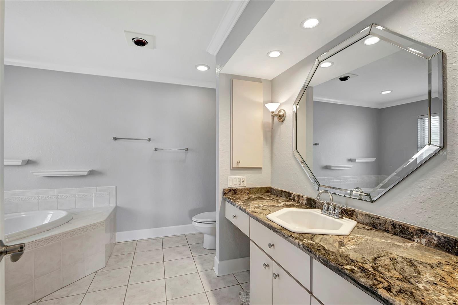 Welcome to the master bathroom, featuring a luxurious tub, stylish sink, spacious mirror, and plenty of cabinets for storage.
