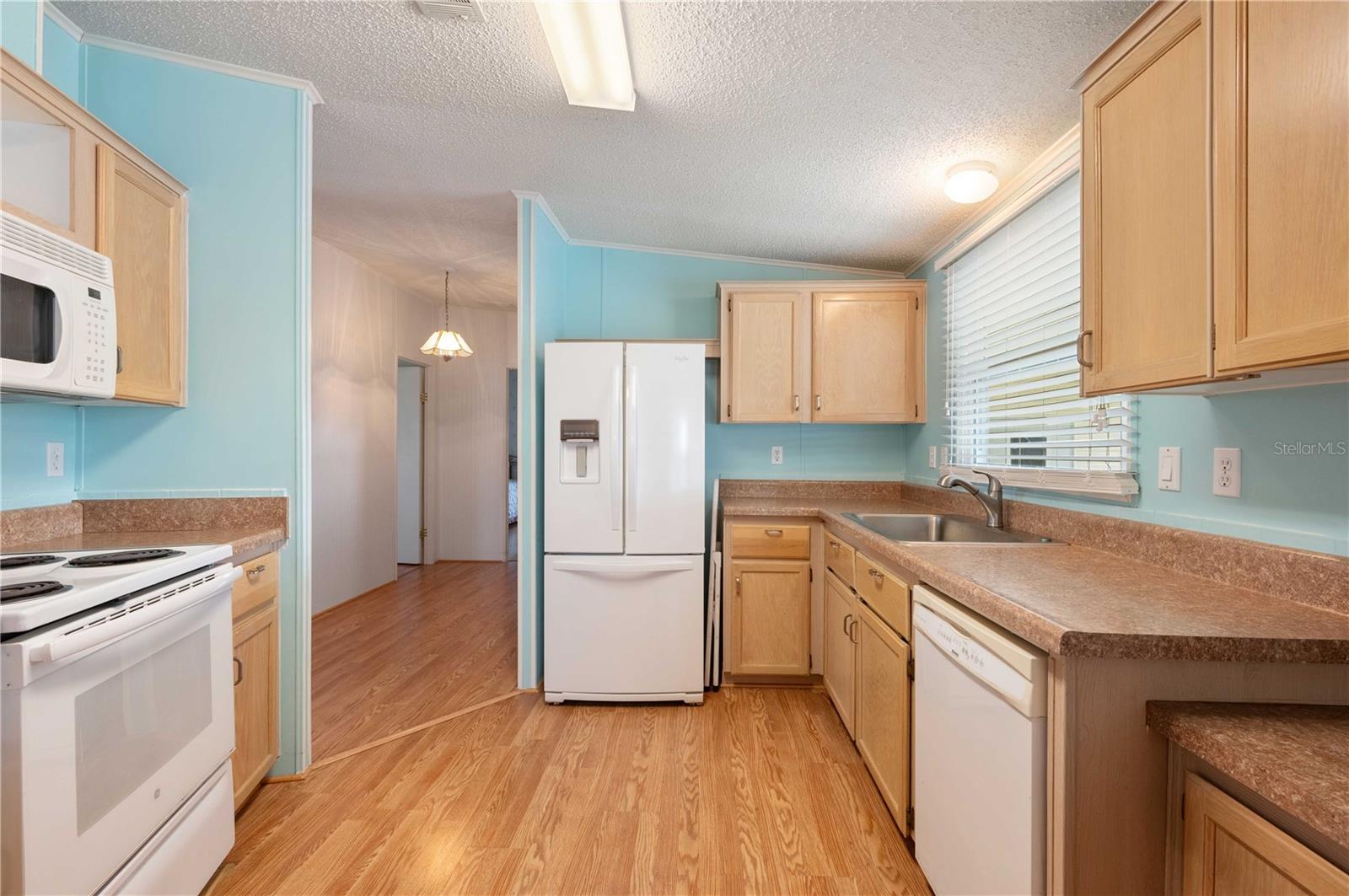 Kitchen has laminate flooring, newer appliances, breakfast bar, and plenty of storage.
