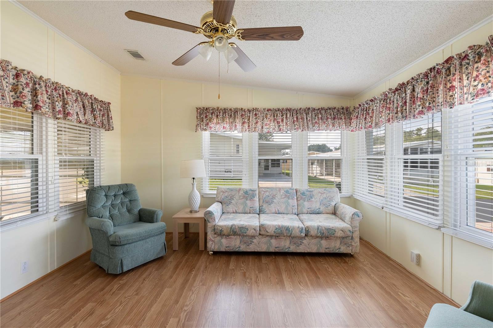 Front Florida room is heated and cooled on central system. Note many double pane windows, ceiling fan, and laminate flooring.