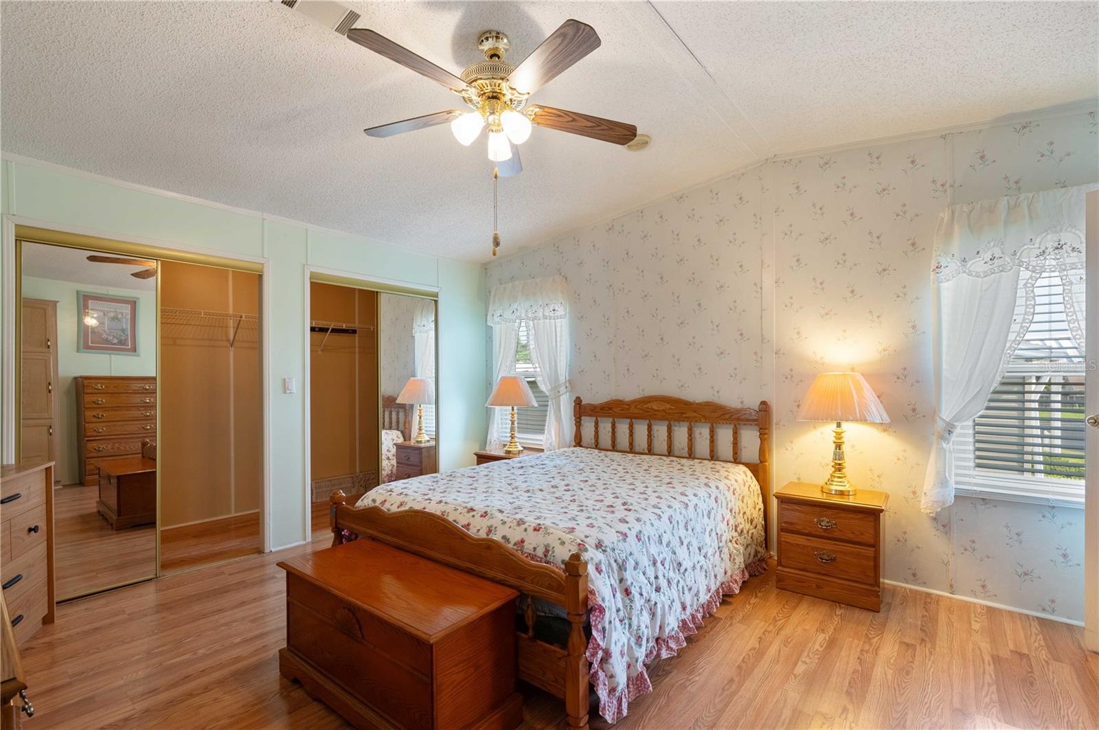 Master bedroom has laminate flooring, ceiling fan, walk-in closet, and plenty of windows.