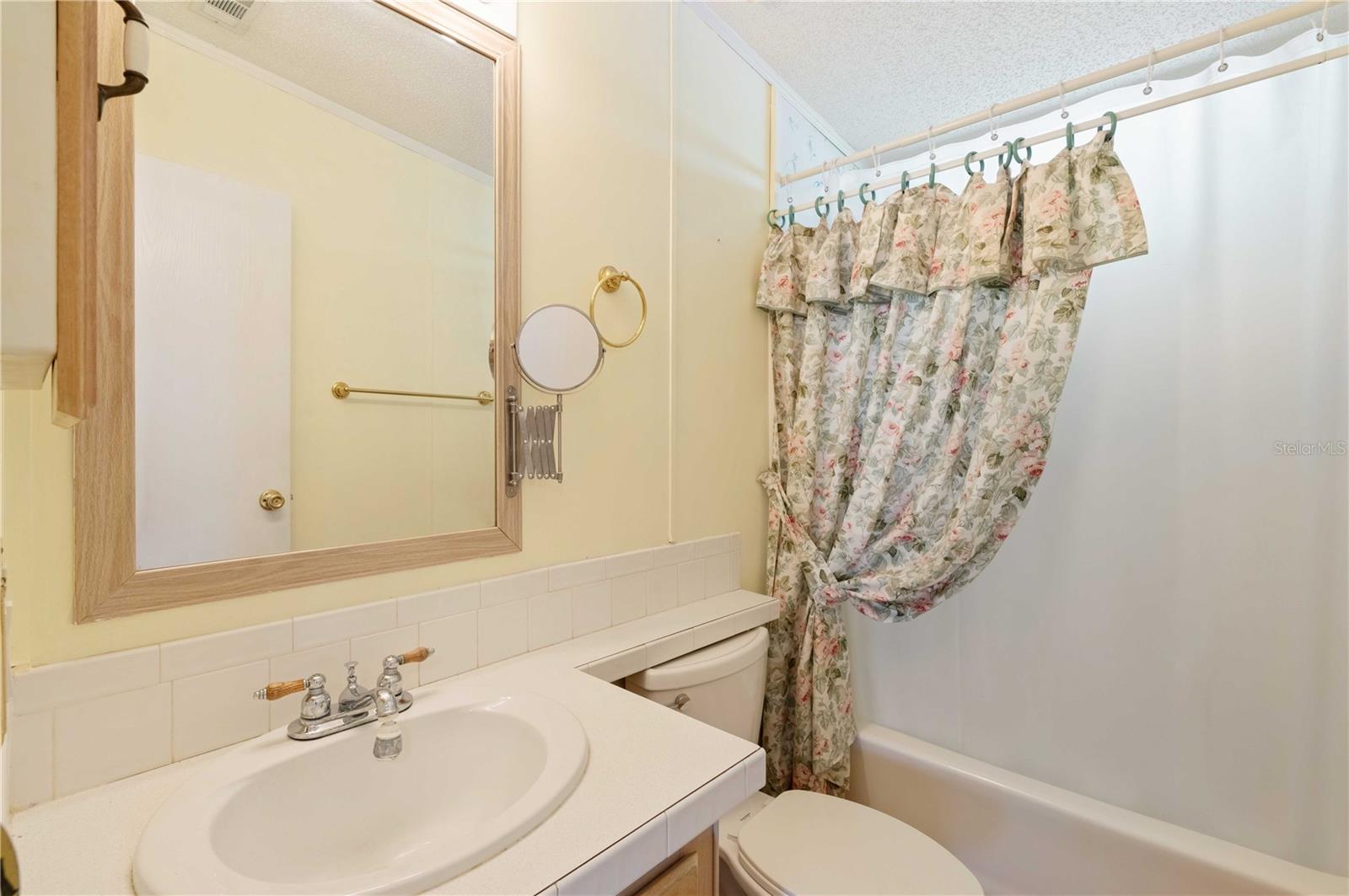 Guest bath has tub/shower combo, high toilet, and laminate flooring.
