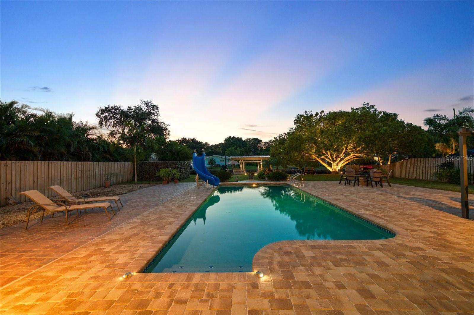 Spacious heated pool and slide surrounded by lots of deck area.
