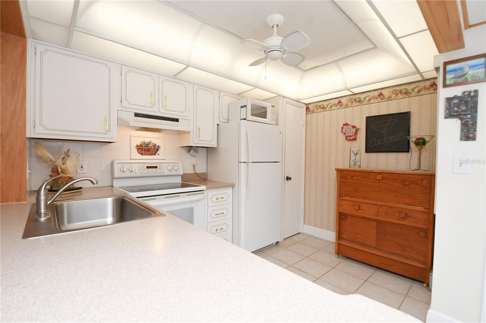 The kitchen includes a light-up tray ceiling with a fan in the middle, an extra-large sink with a garbage disposal, and a beautiful Corian countertop.