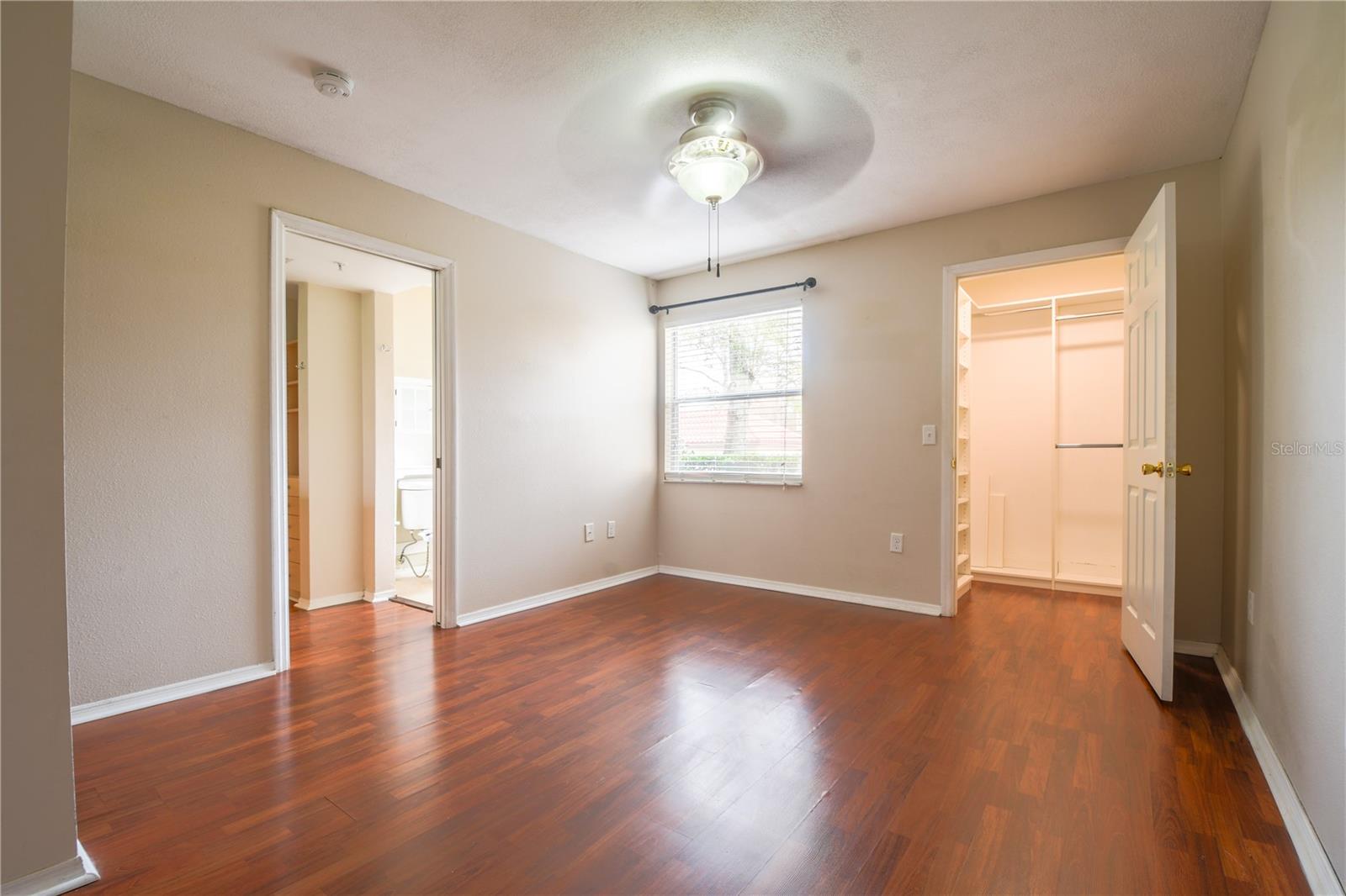 The primary bedroom features wood laminate flooring, a ceiling fan and ensuite bath.