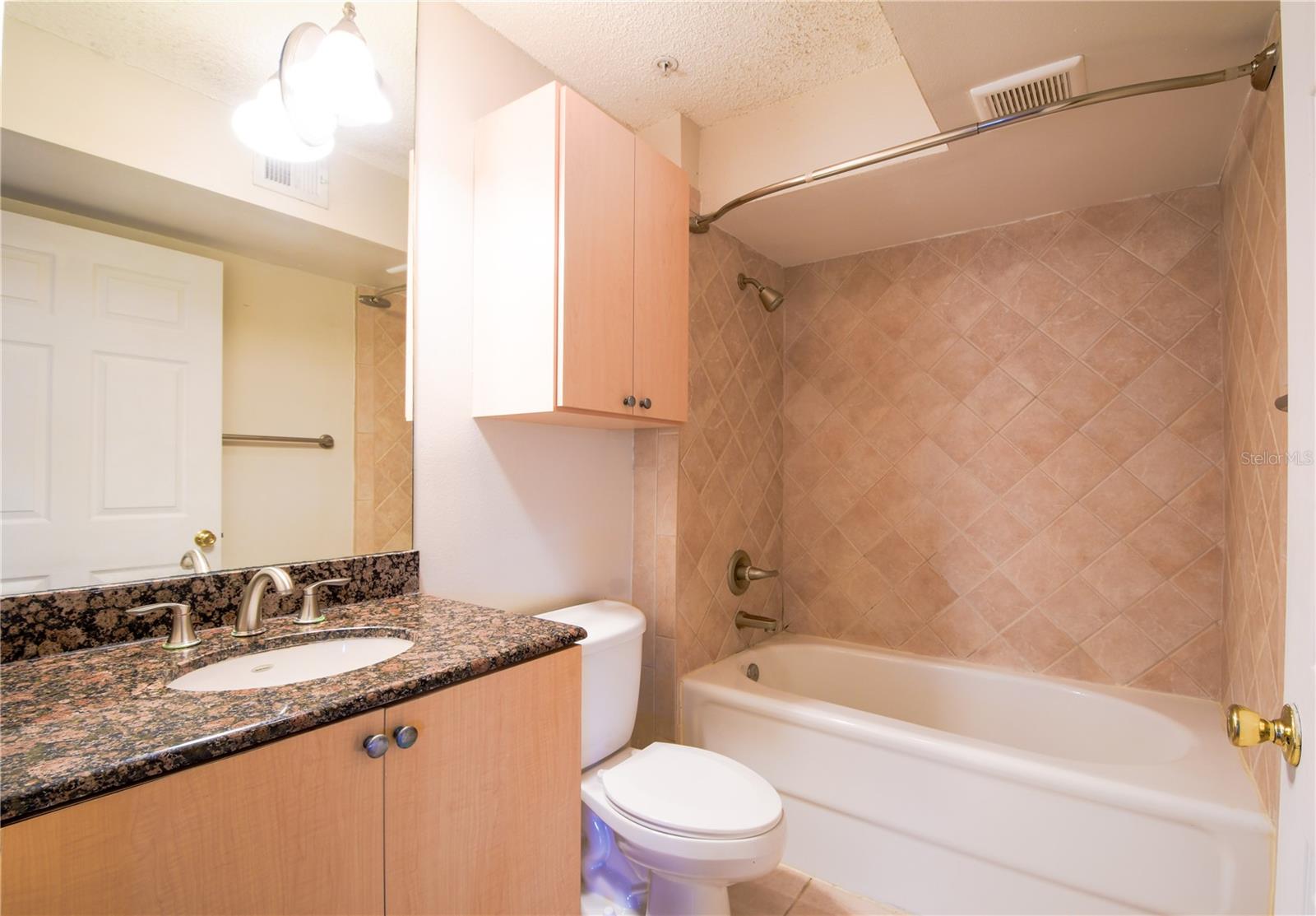 Bathroom 2 features ceramic tile, a mirrored vanity with storage, granite countertop, and tub with shower.