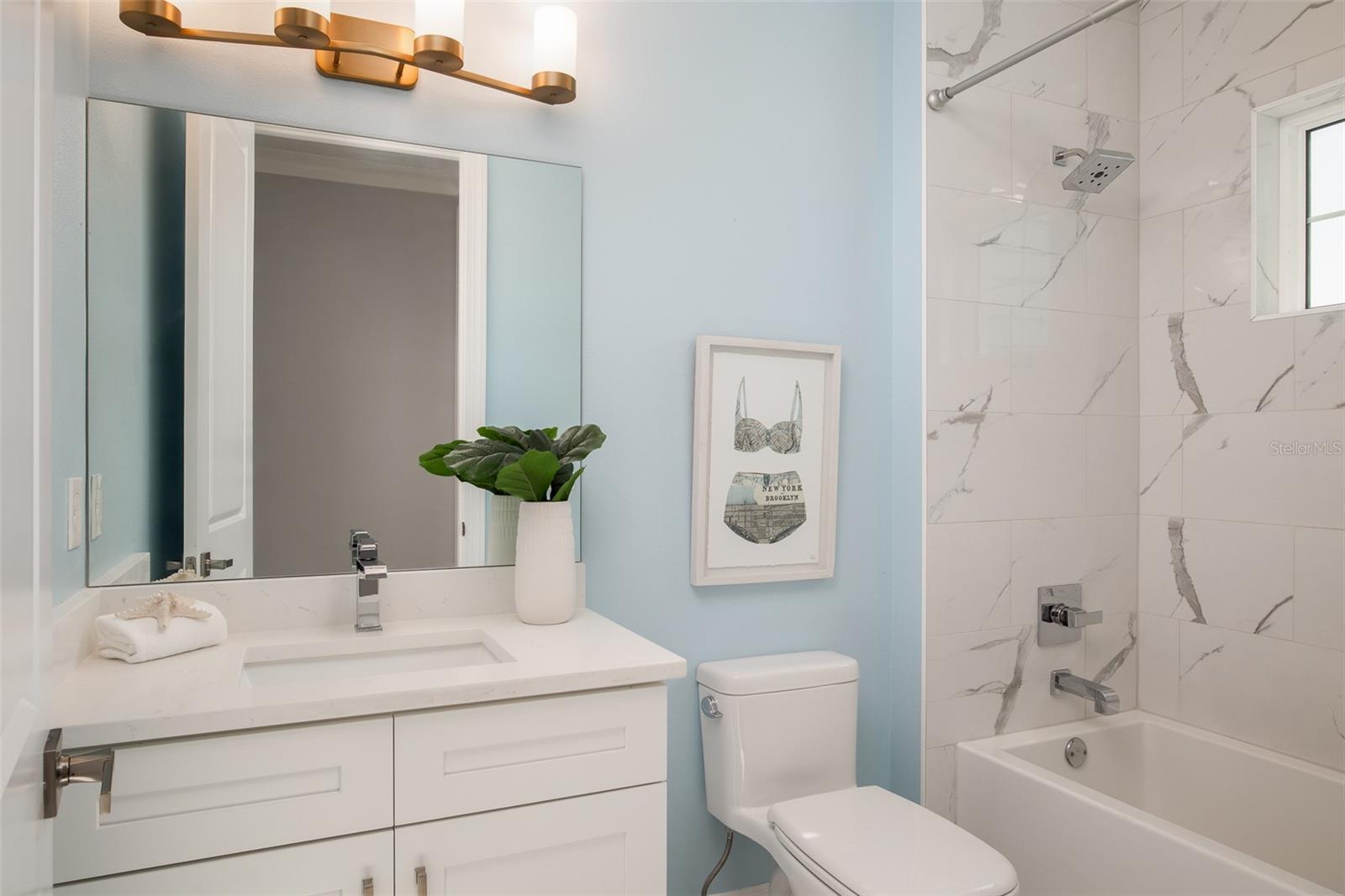 Indulge in the opulence of the first full bath, adorned with luxury stone countertops, offering a refined touch of coastal elegance and sophistication to your daily routine.