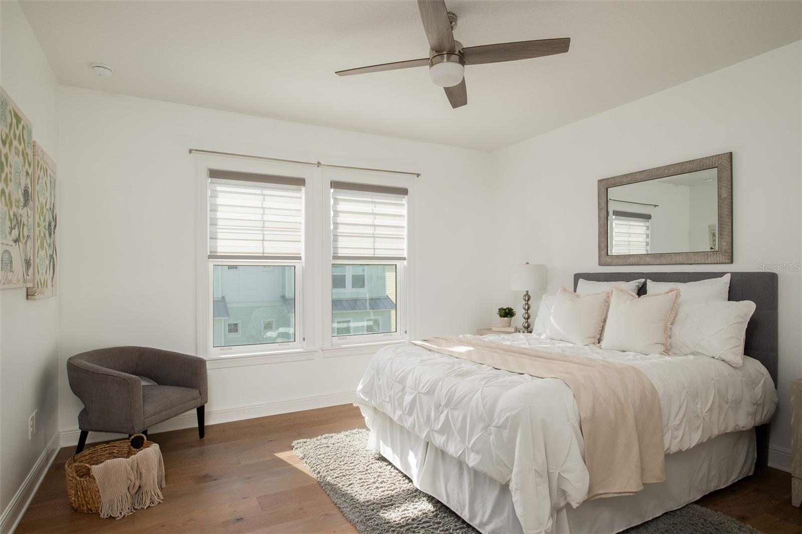 The second owners suite offers a tranquil escape, featuring a ceiling fan and abundant natural lighting, providing a serene haven within your coastal home for ultimate relaxation and comfort.