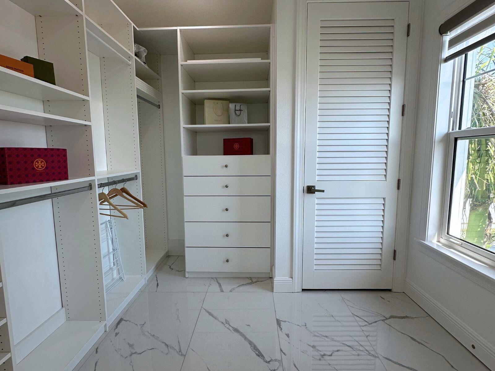 Enjoy the convenience and luxury of the massive walk-in closet in Master Suite 2, complete with custom built-ins, providing ample storage space and organization for your wardrobe essentials in your coastal retreat.