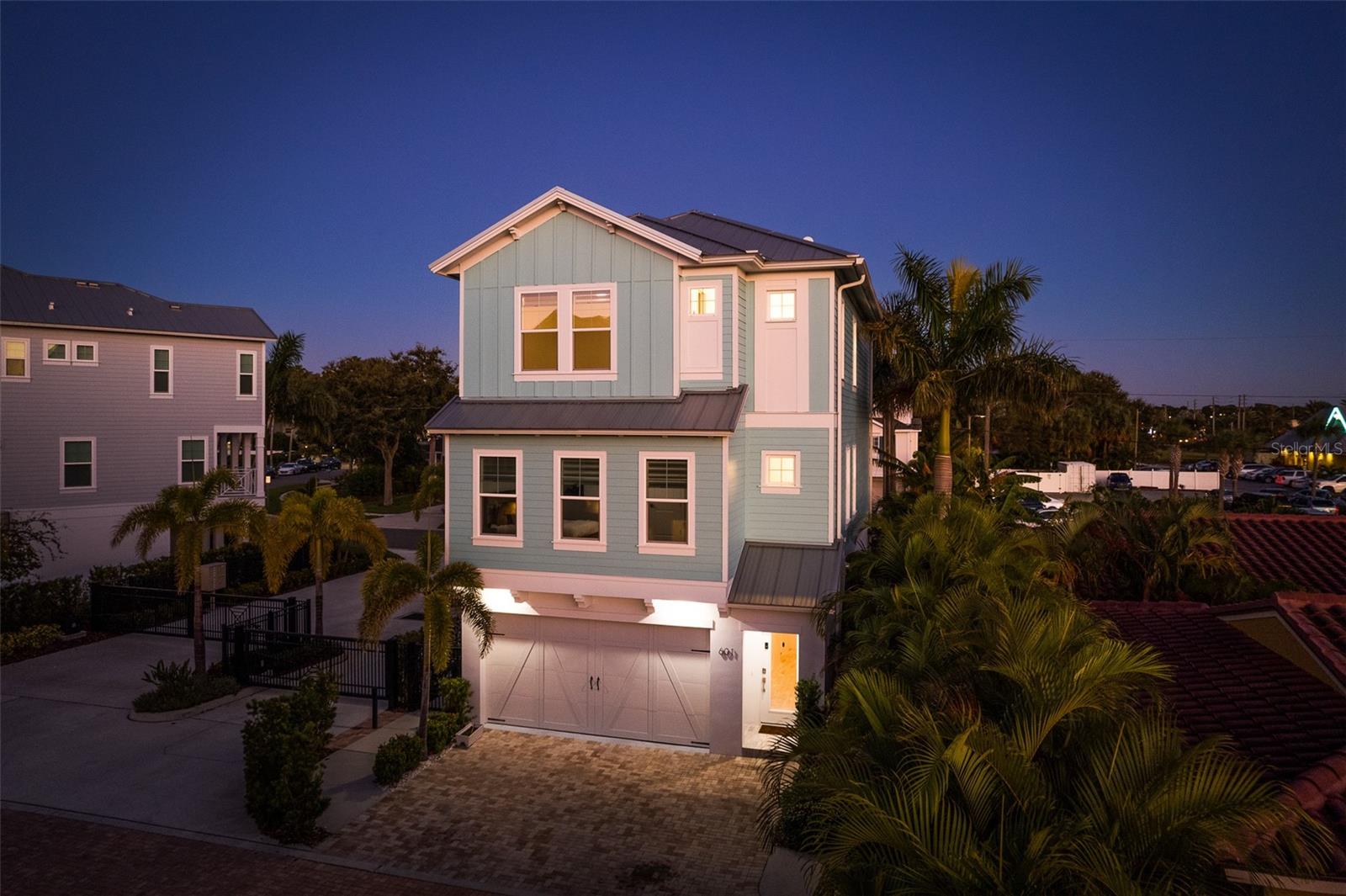Capture the enchanting beauty of the coastal townhome with twilight photos, showcasing the allure of the Tiffany blue facade illuminated by the soft glow of evening light, inviting you to embrace the serenity and elegance of coastal living.