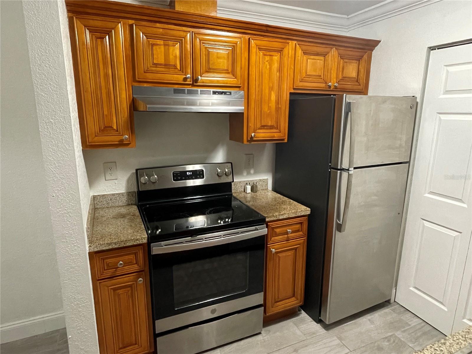 Glass top range, crown moulding, SS fridge, enhance the kitchen. Door on the right opens to laundry hookups.