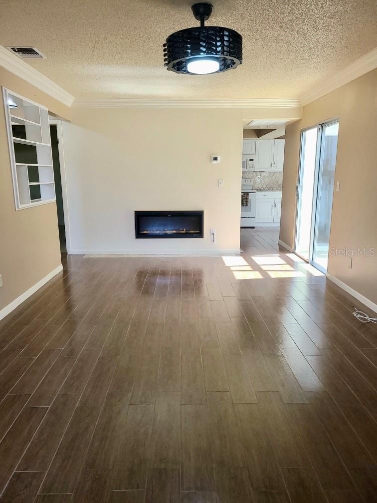Upon entering, you will be greeted with plenty of natural light that showcases the wood-like tile flooring, electric fireplace, new crown molding, new contemporary ceiling fan, and desirable split floor plan.