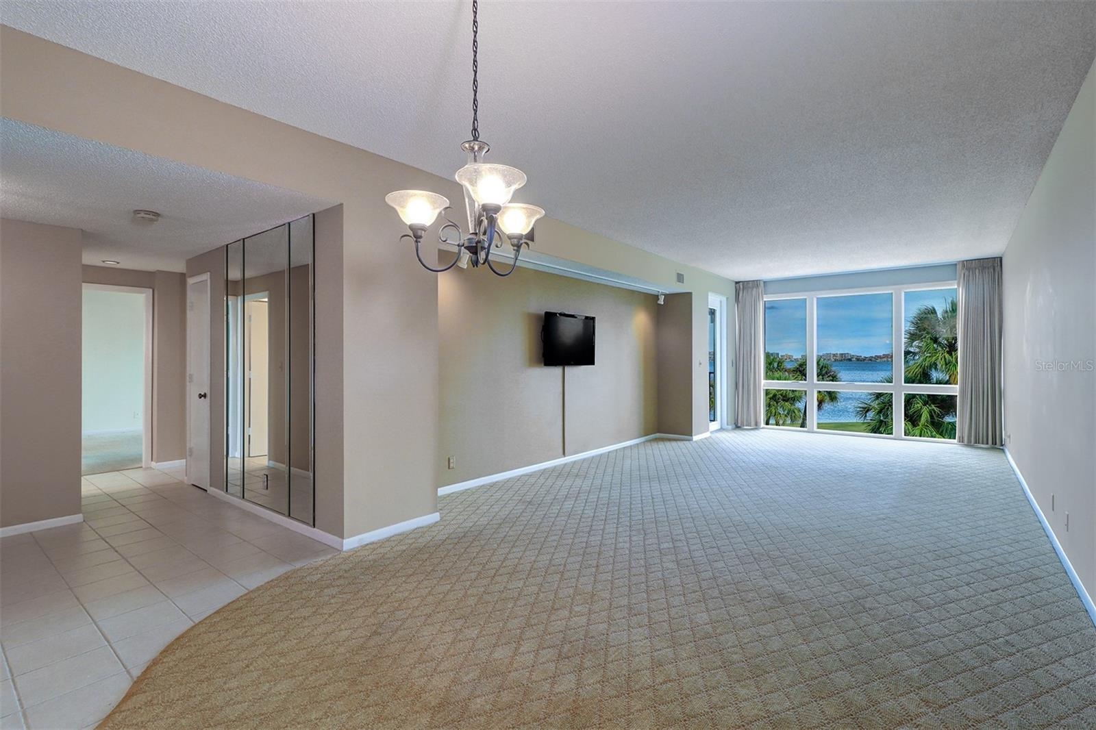View of entry hall to the left, dining and living area to the full glass wall of water views