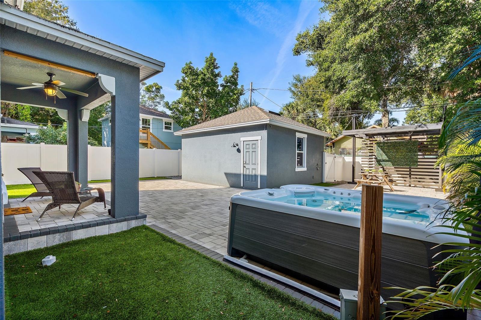 Backyard retreat with newer hot tub, outdoor shower, pavers, turf, and detached garage with alley access.