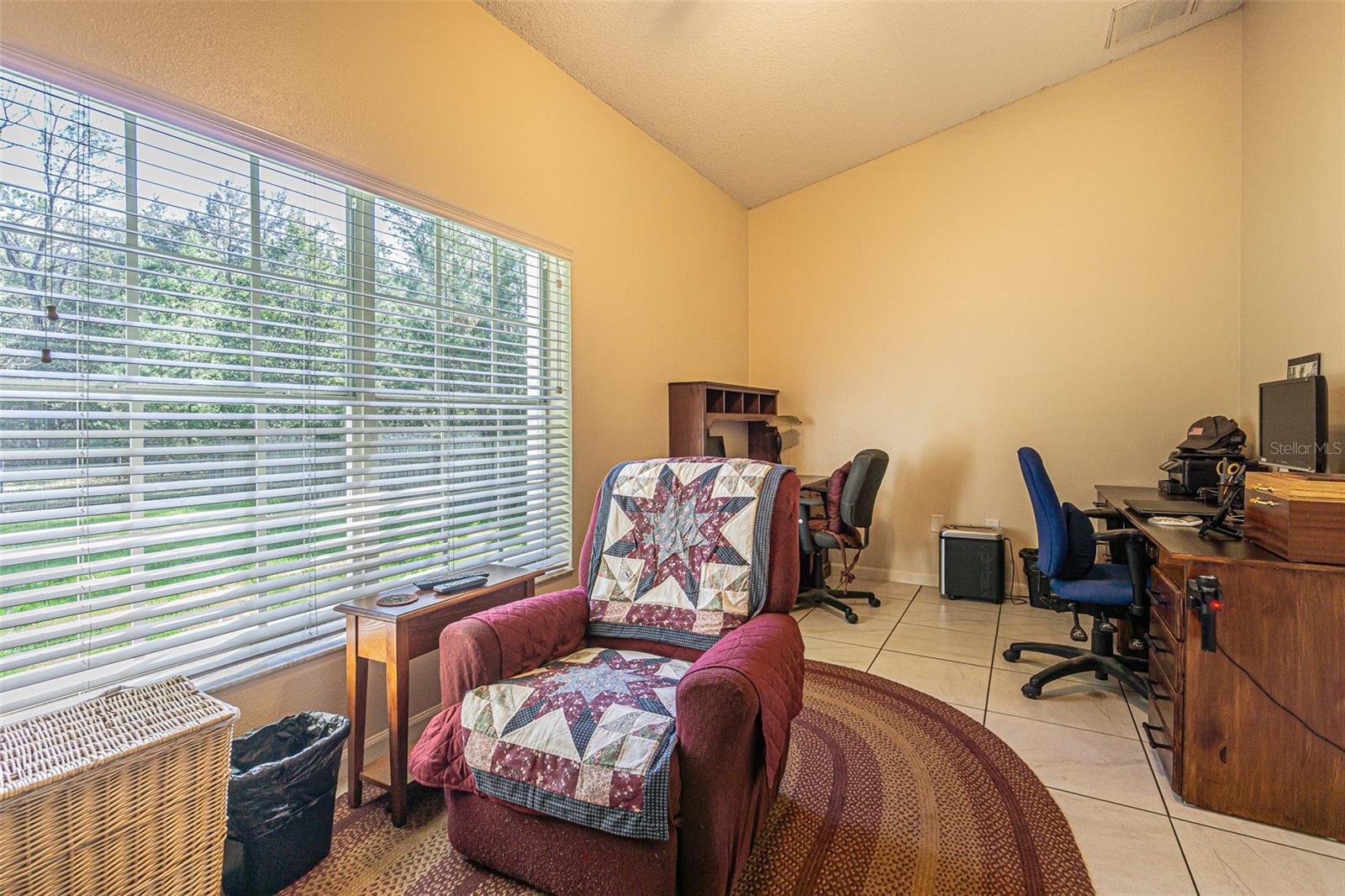 Den/office with gorgeous wooded view of the front yard, specifically the separately fenced area.
