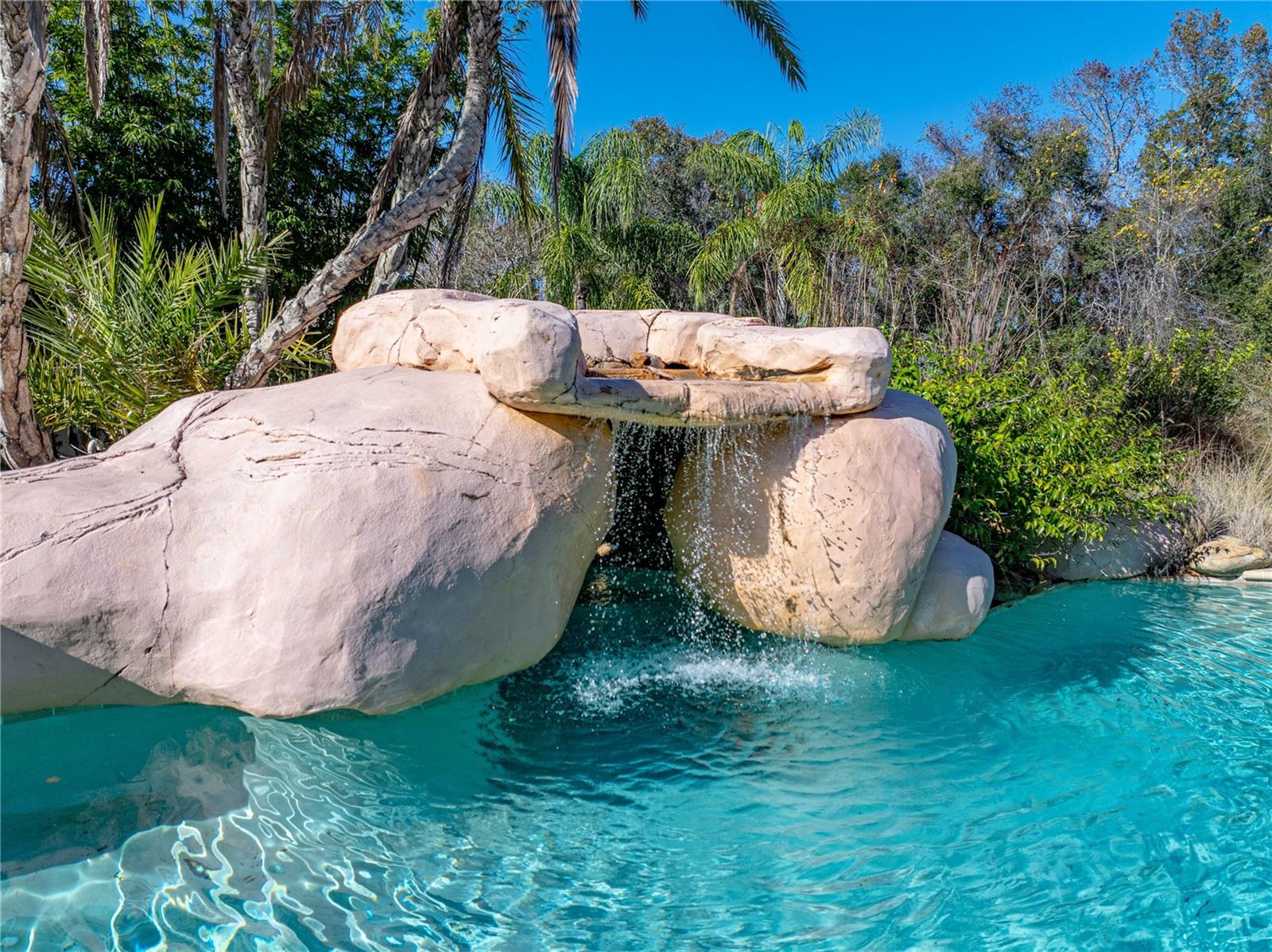 Custom, freeform pool features rock ledge waterfall and cove