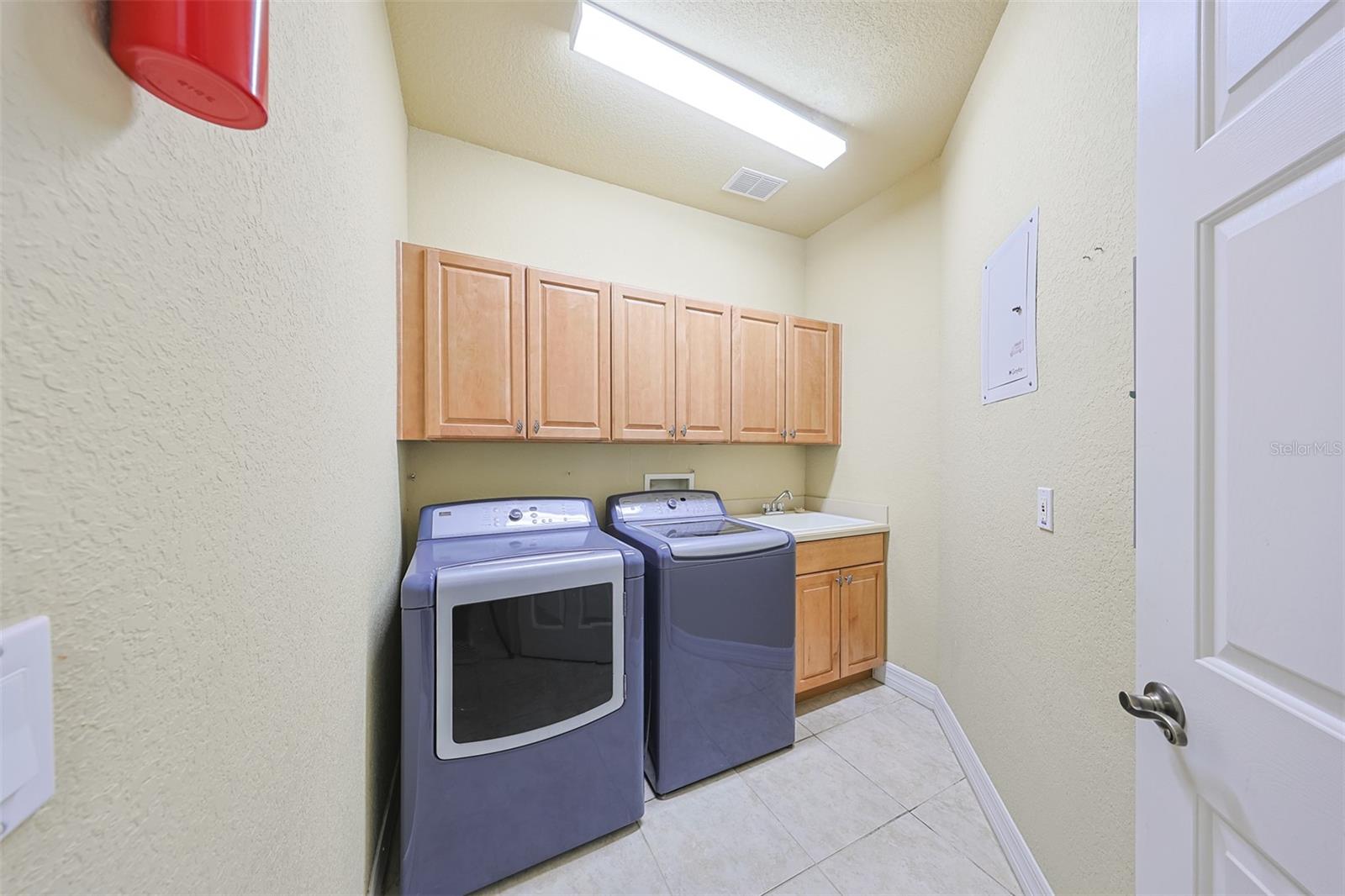 Separate indoor laundry room with lots of cabinets for storage, good lighting and a utility sink make the task of doing laundry easier.