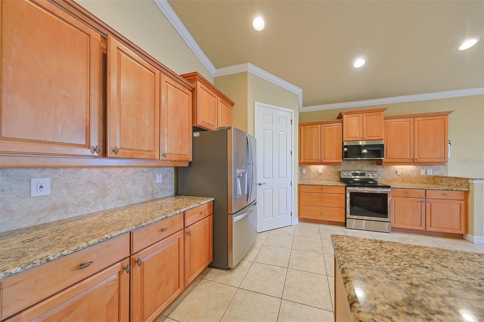 The abundant kitchen cabinets are a handsome honey oak color, with pull out drawers and a large walk-in pantry closet.  Notice the 10' ceilings, recessed lights and lovely crown molding.