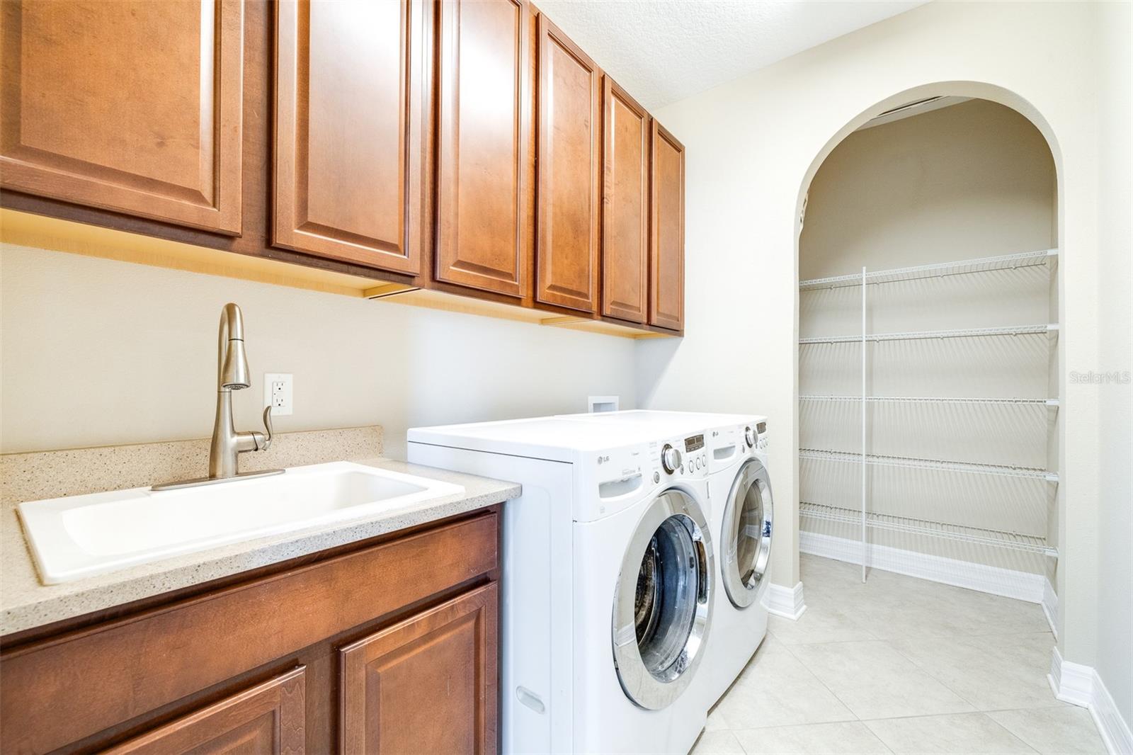 Laundry room with extra cabinets, utility sink, and walk-in storage room/closet