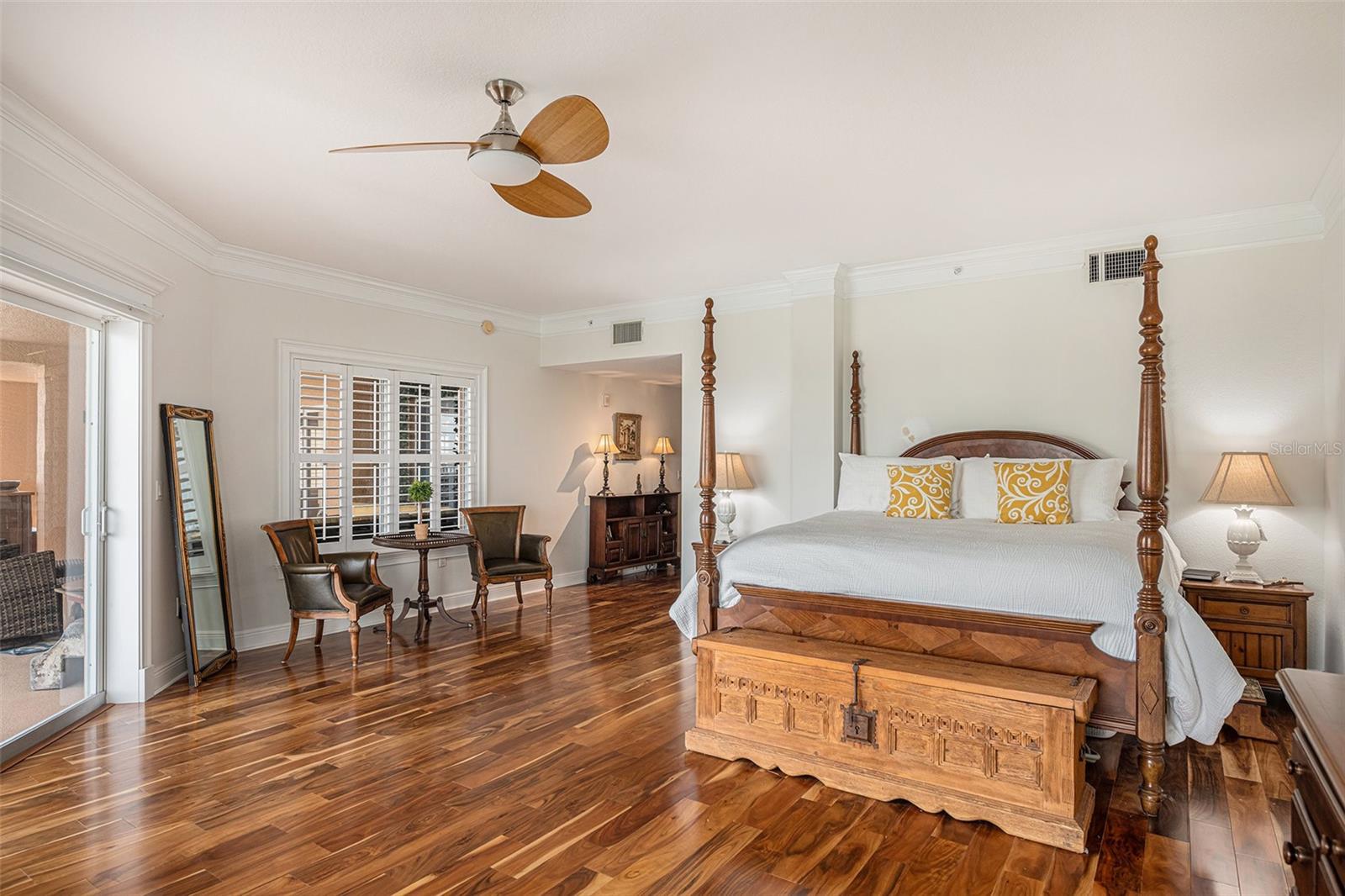 Stunning wood floors, plantation shutters, and crown molding accent the beauty of this primary bedroom.