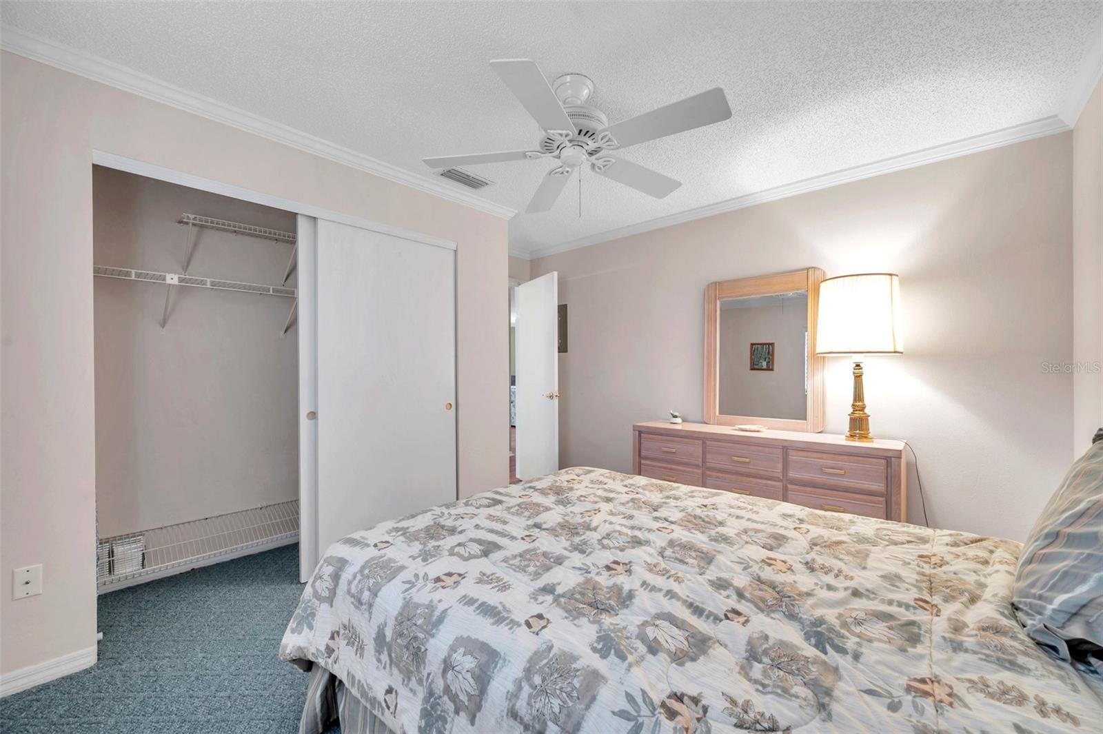 Guest bedroom has a double size closet, ceiling fan and carpet.