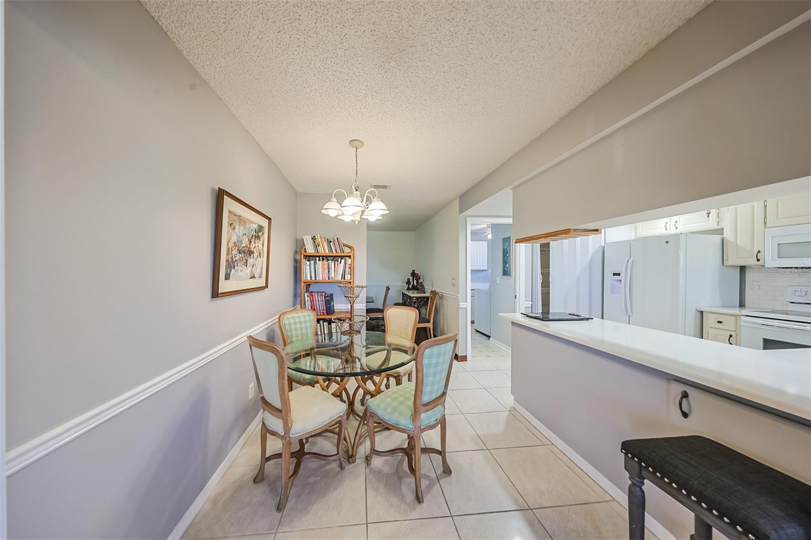 Kitchen includes newer appliances, lots of lovely Corian countertop space, a pantry along a full wall and a large pass-through window so that you can see/talk to anyone in the Florida room or enjoy the vast green space and Florida sunshine outside.
