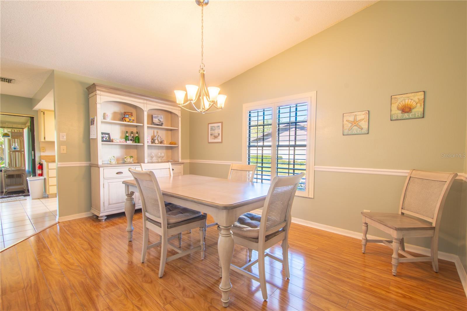 The dining room features an stylish chandelier and plantation shutters
