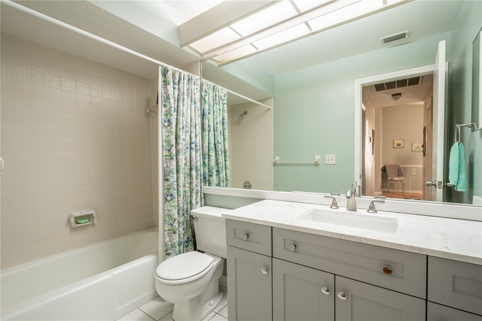 Bath 2 features a tub with shower, mirrored vanity with storage and ceramic tile floor.