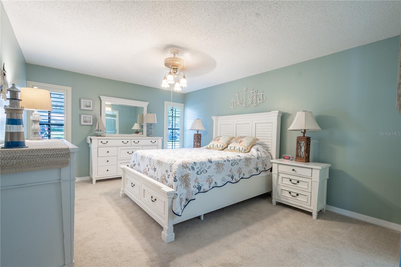 The freshly painted primary bedroom features, neutral carpet, plantation shutters, a ceiling fan with light kit, a walk-in closet and ensuite bath.