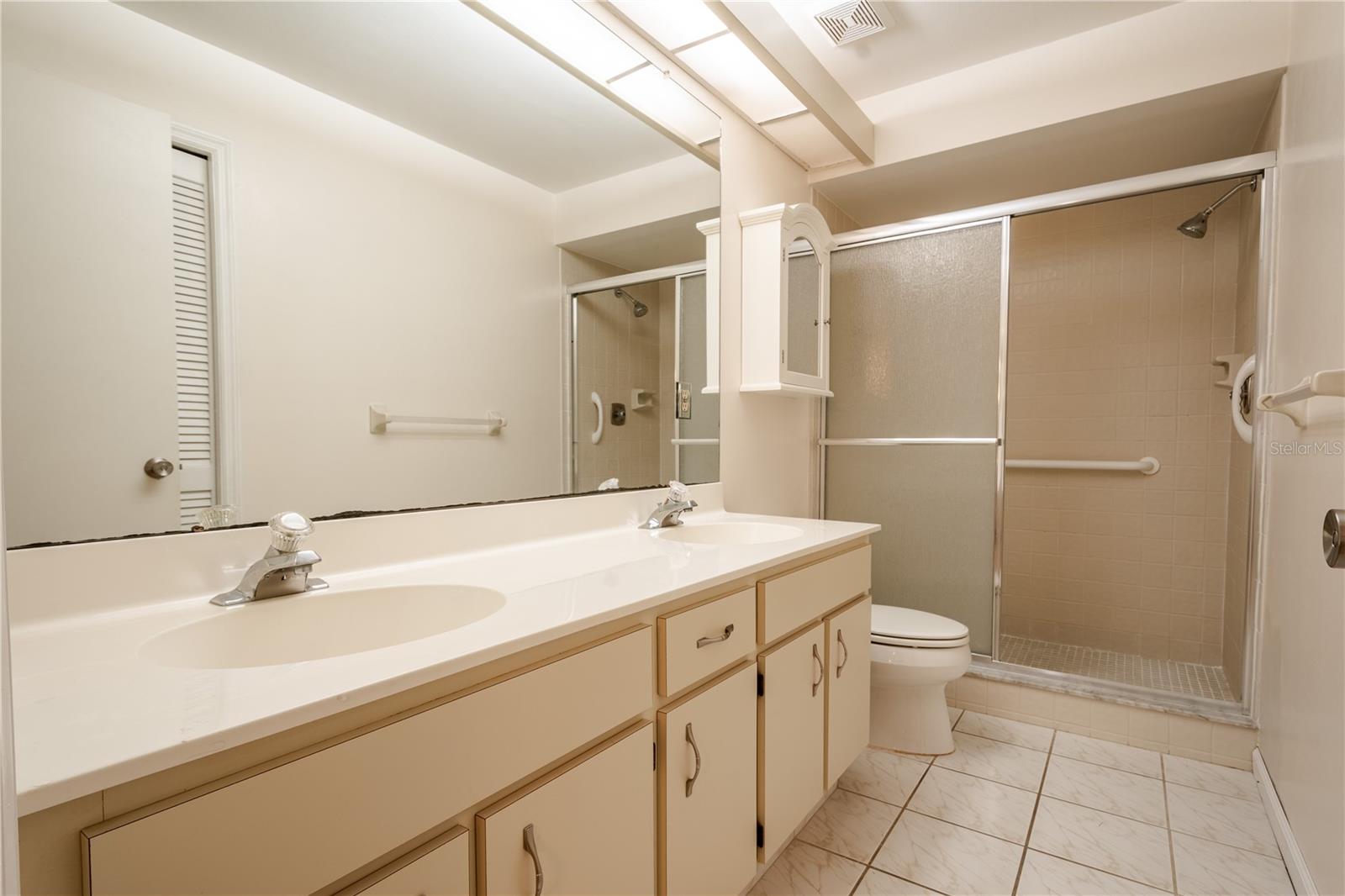 he ensuite bath includes a walk-in shower, a dual sink vanity with storage, and a linen closet.