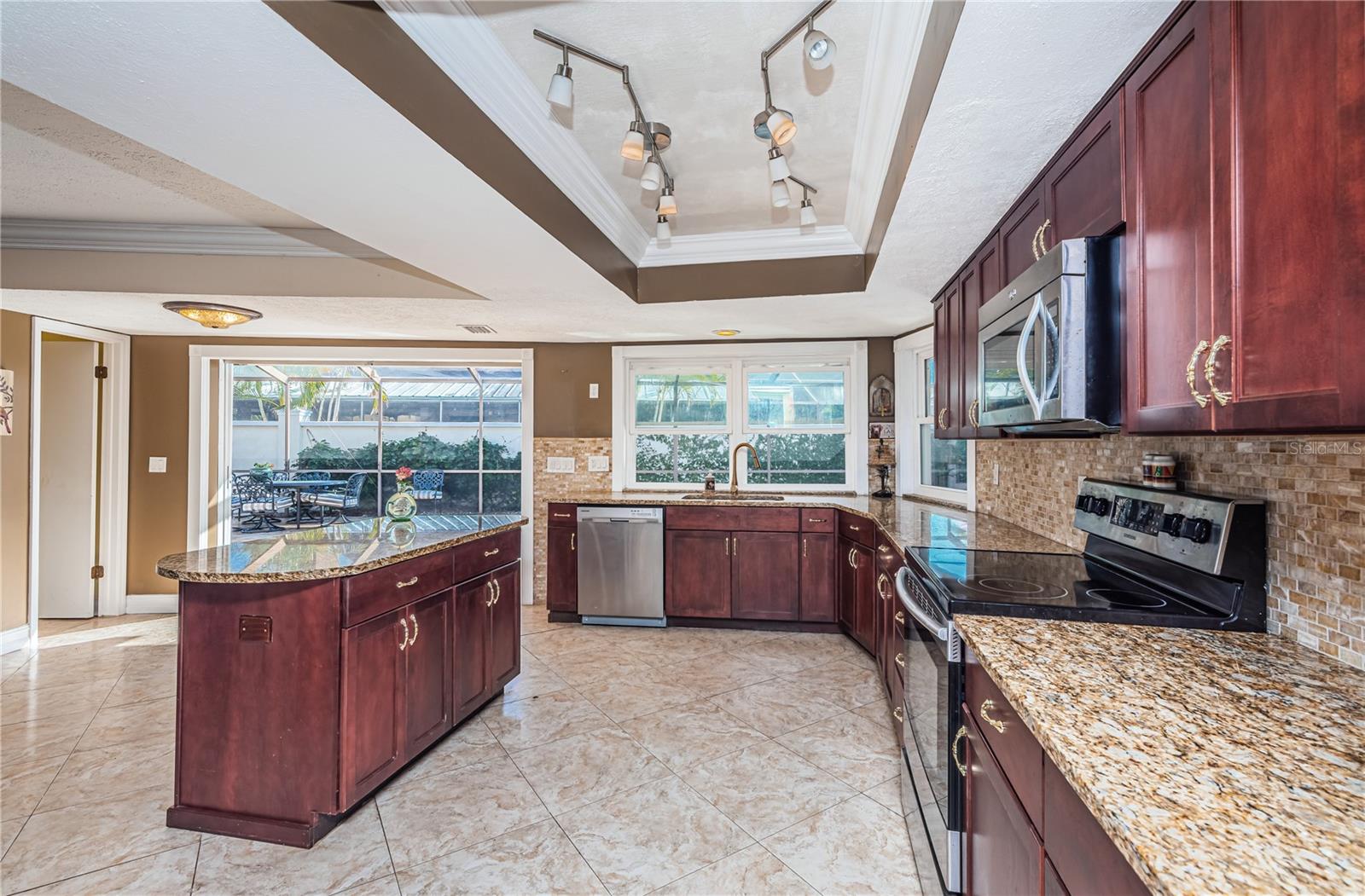 Abundant kitchen with granite counters, onyx tile backsplash and wood cabinetry...all looking out toward the lanai.