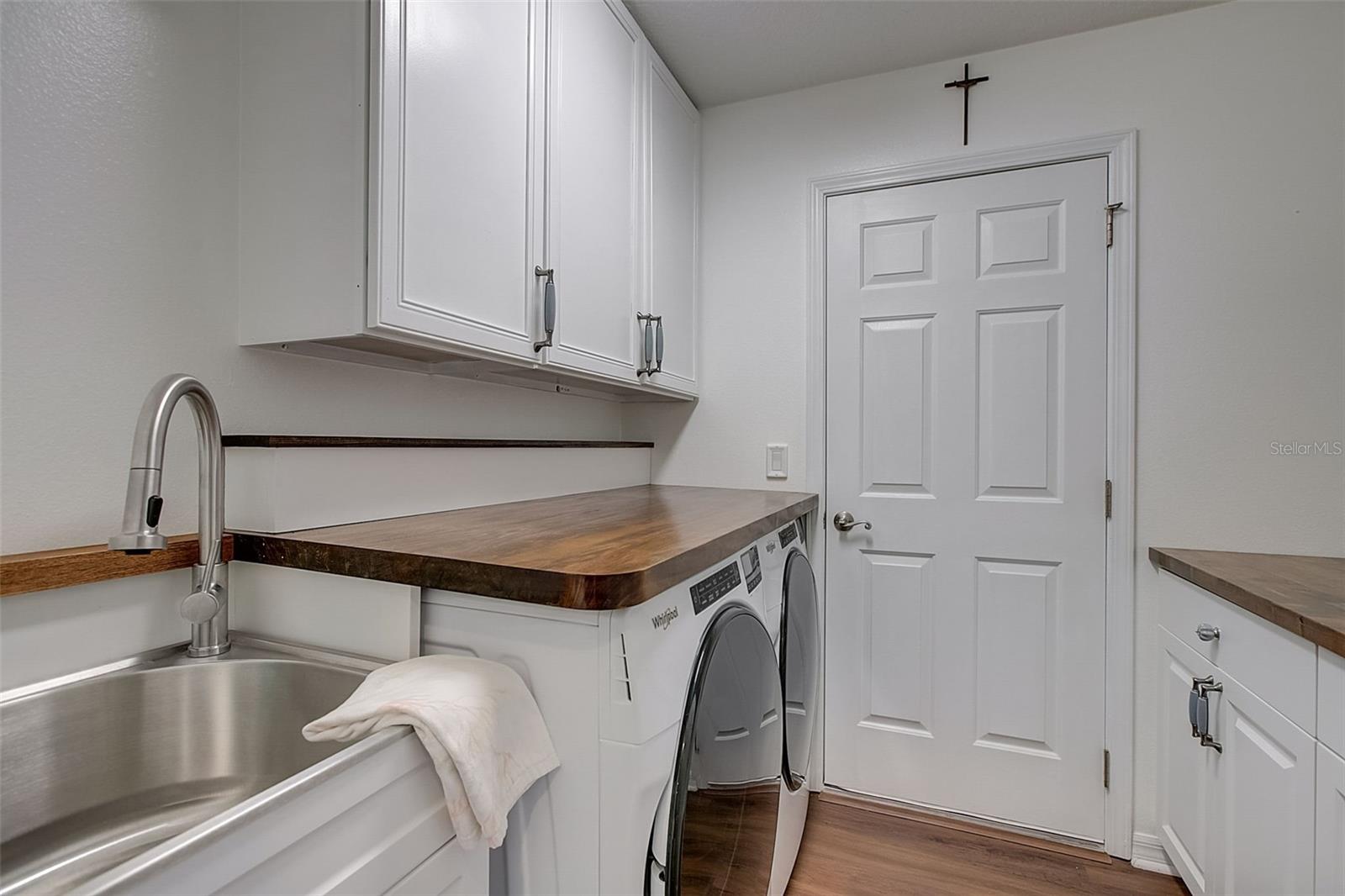 Laundry room with utility sink, built-in shelving, and cabinets with butcher block counters