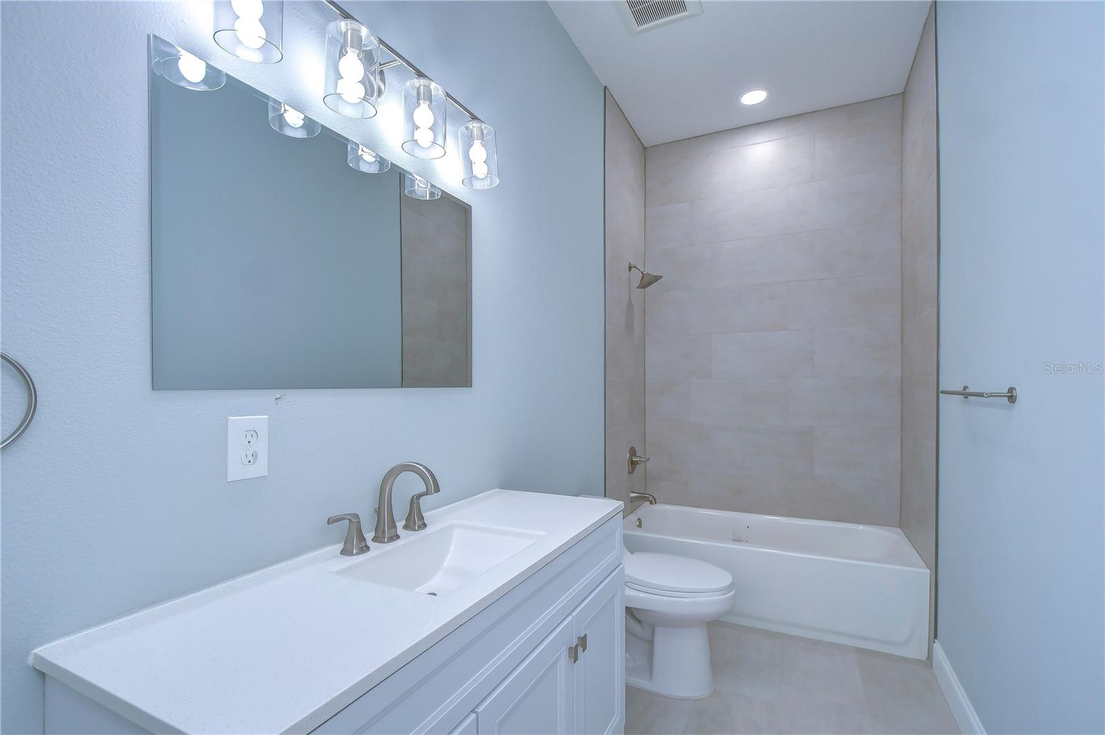 The hall bathroom features a large vanity with quartz countertop and bathtub for soaking your cares away.
