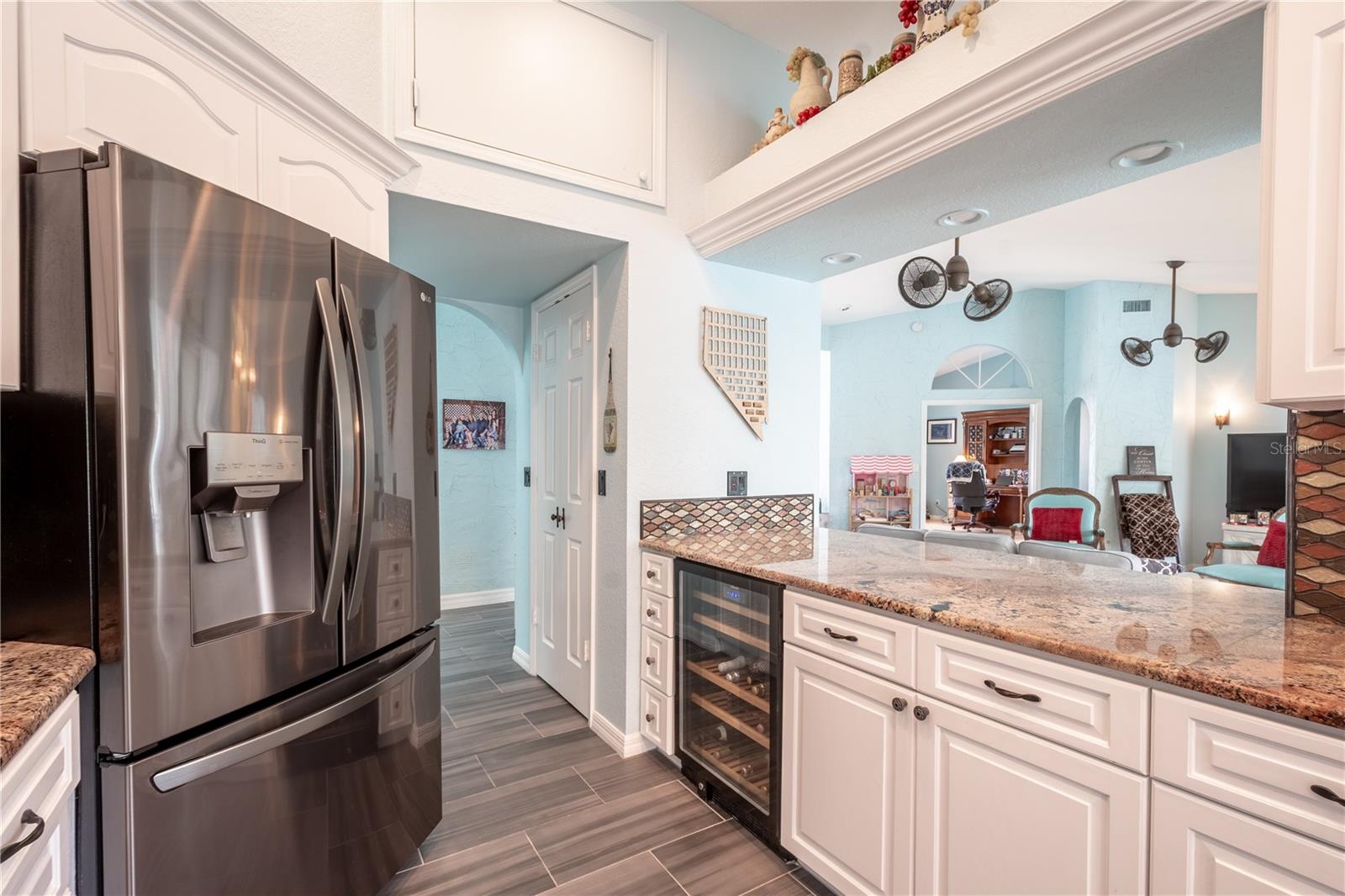 The kitchen features a ceramic tile wood plank floor, recessed lighting and a full suite of appliances including a wine fridge.