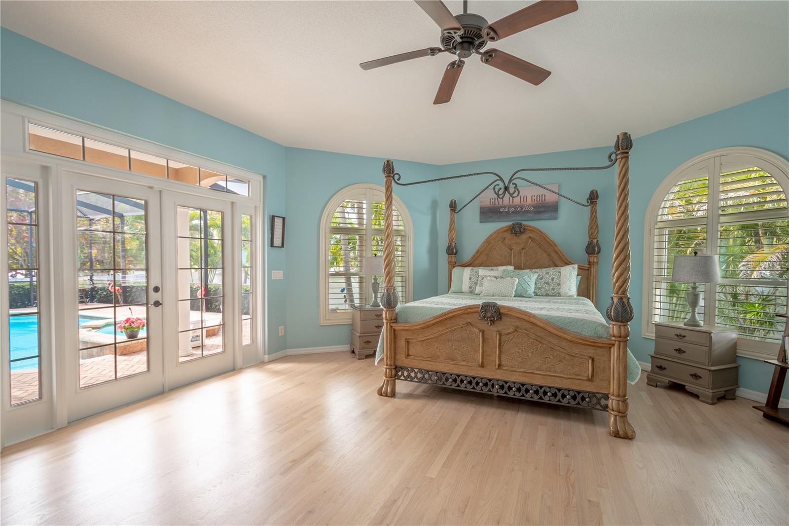 HThe spacious primary bedroom features high ceilings with ceiling fan and wood floors.