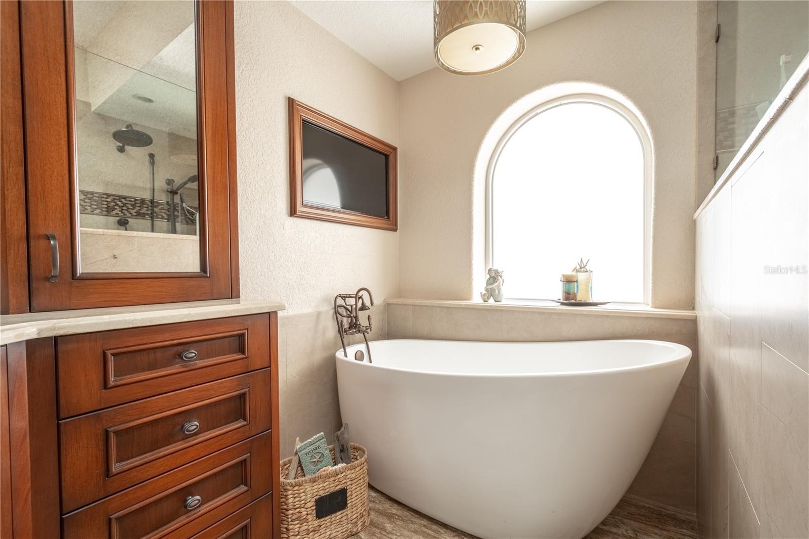 The en-suite bath features his and hers mirrored vanities in wood cabinetry.