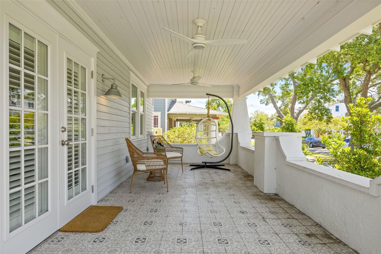 Charming front porch is the epitome of old NE style. Notice the gorgeous tile flooring and fans!