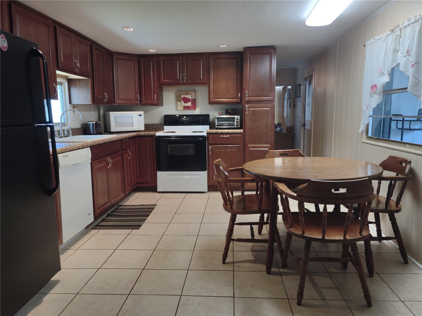 Eat in kitchen features tile flooring, rich chestnut cabinetry, granite looking countertops, inset can lighting, updated appliances (refrigerator, dishwasher, range, countertop microwave) and a pantry.
