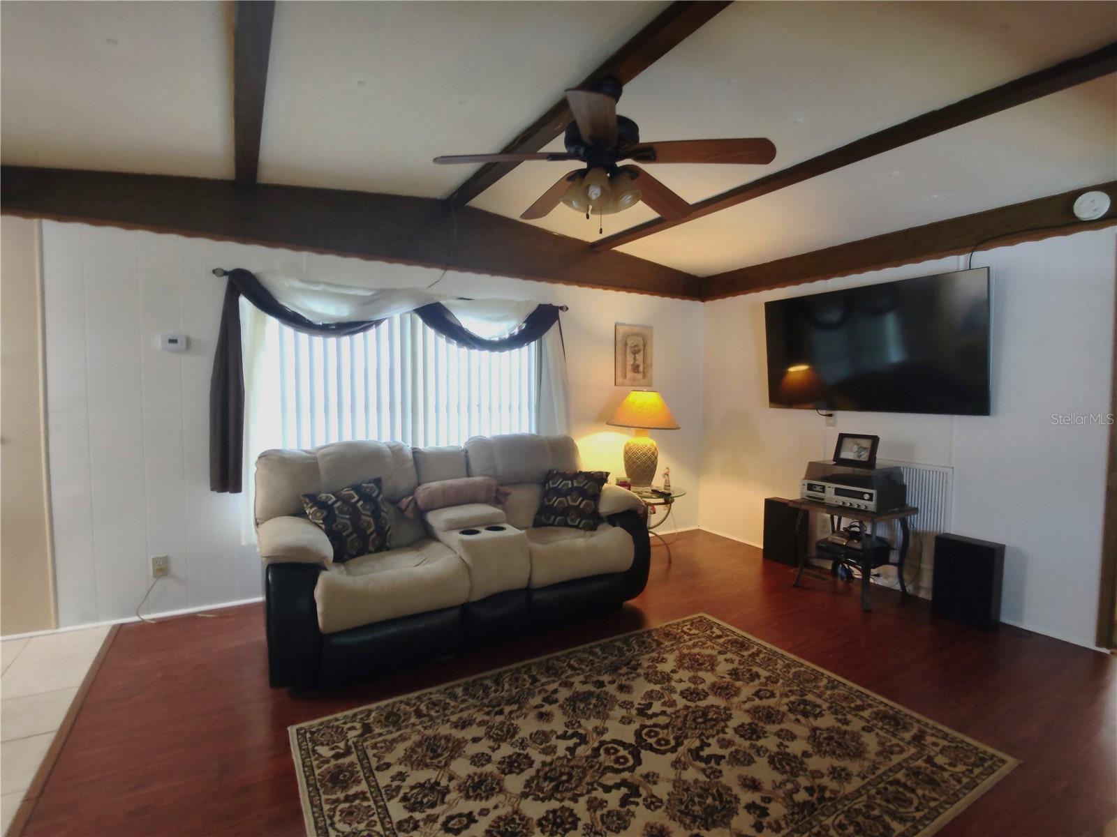 Recently painted living area features gorgeous wood laminate flooring, ceiling fan and a vaulted ceiling.