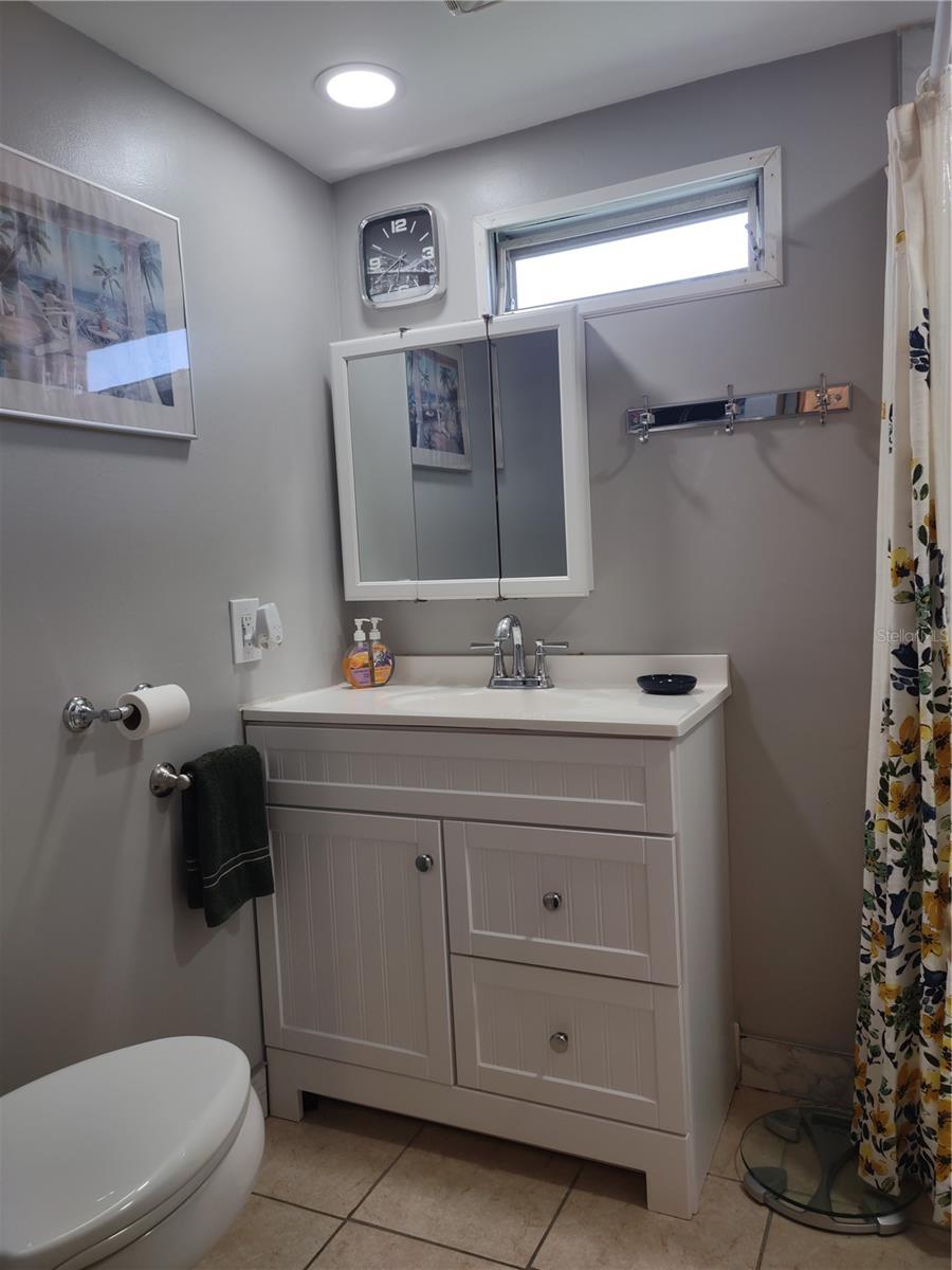 White shaker style vanity with sinktop, medicine chest mirror, commode and hardware all part of the update.