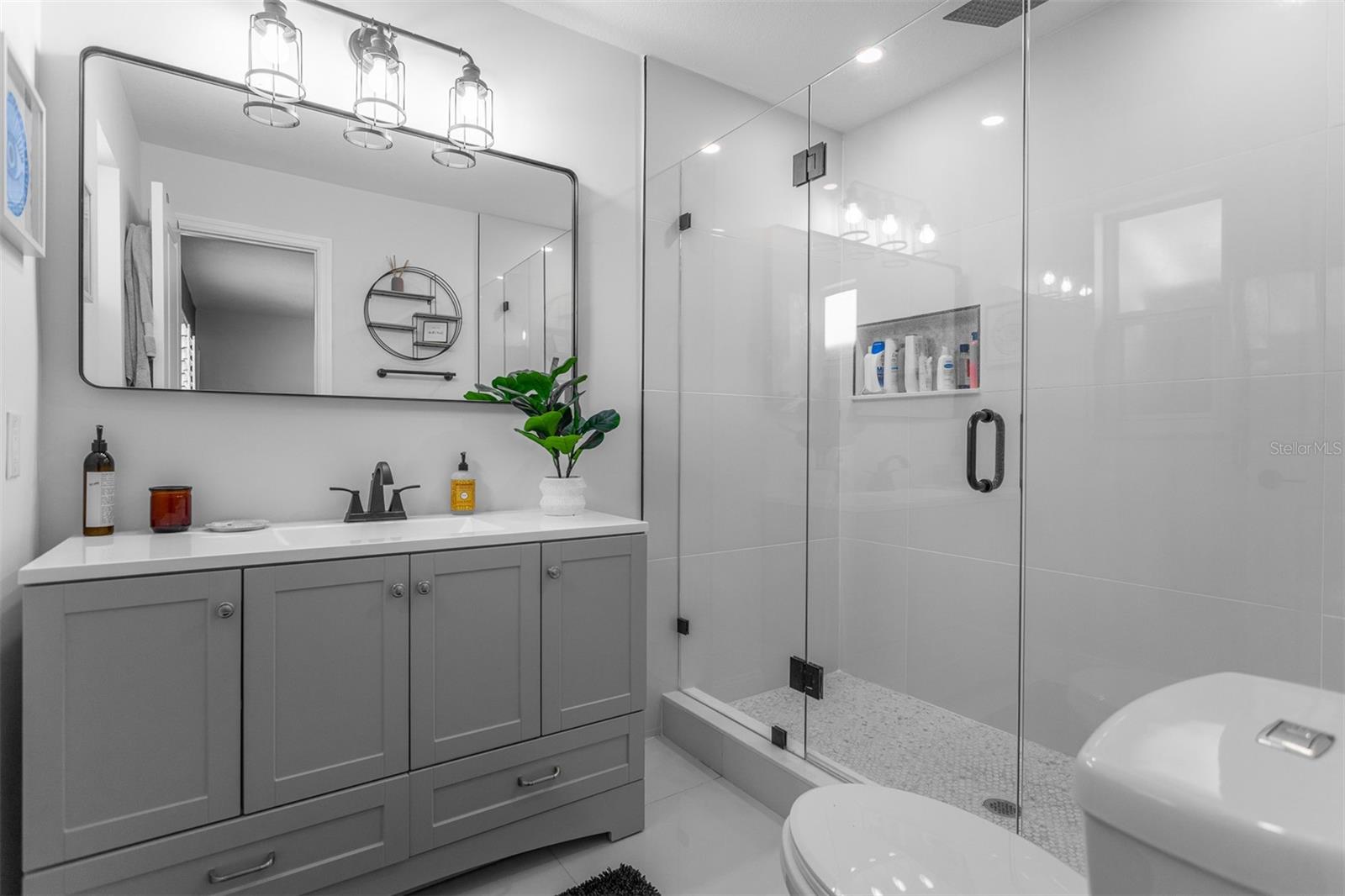 Masterfully renovated master bathroom with seamless glass entry
