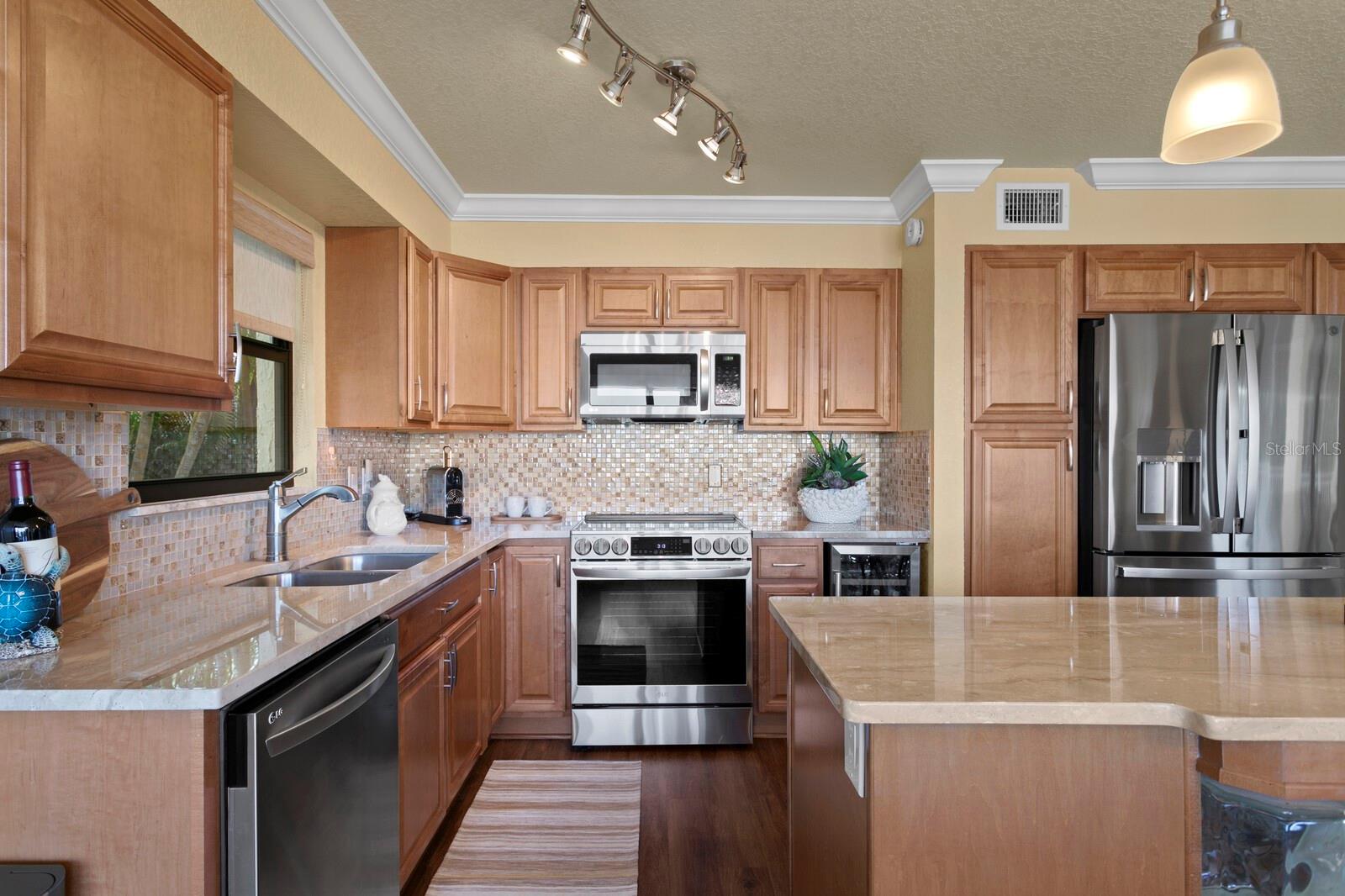 Stainless steel upgraded appliances, including wine refrigerator, and kitchen island with sitting spaces.