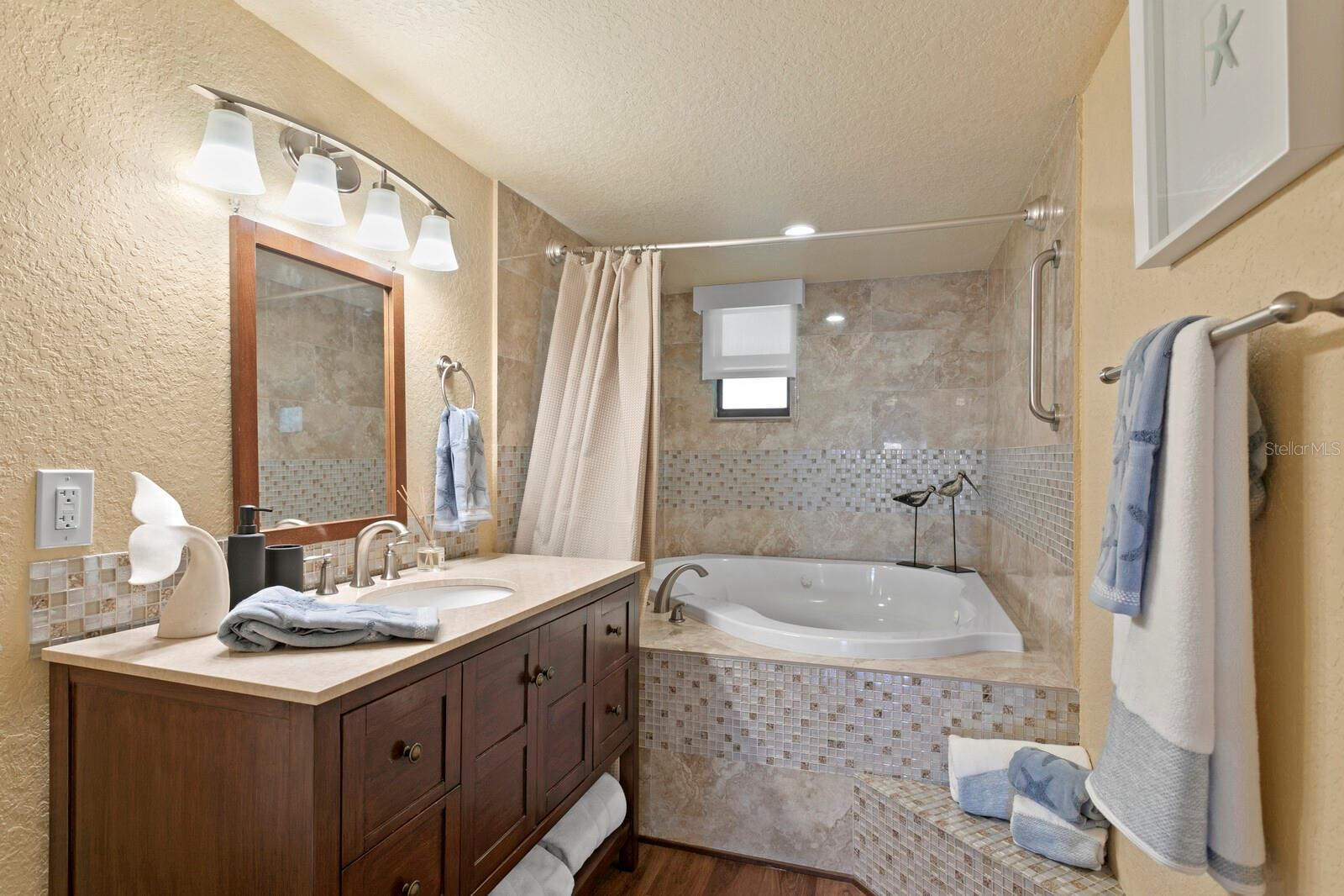 Ensuite Primary Bedroom Bathroom with Jacuzzi tub, shower, and updated tile.