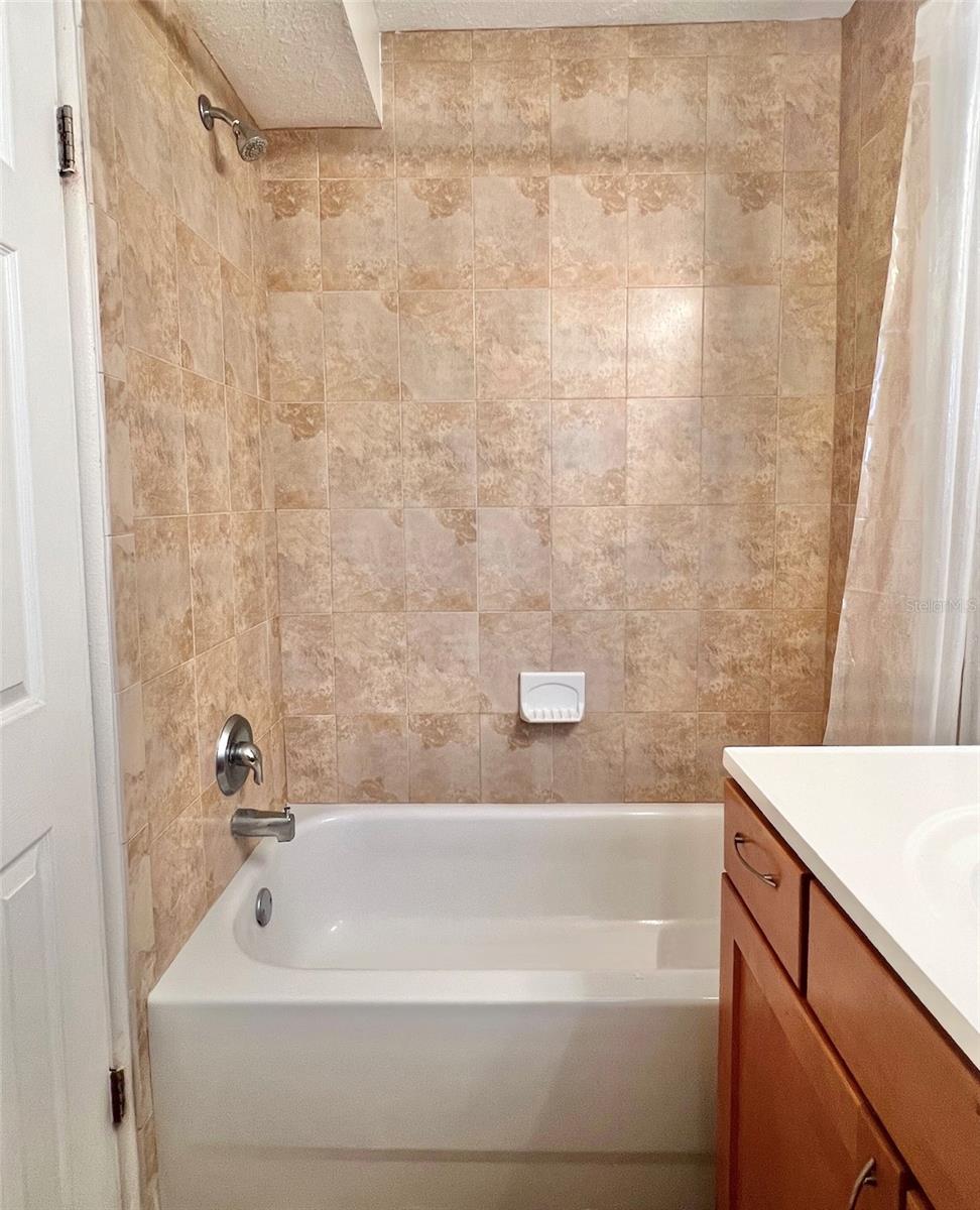 The bathroom features an updated vanity with storage drawers, LED lighting, a tiles tub/shower combo, and tiled flooring.