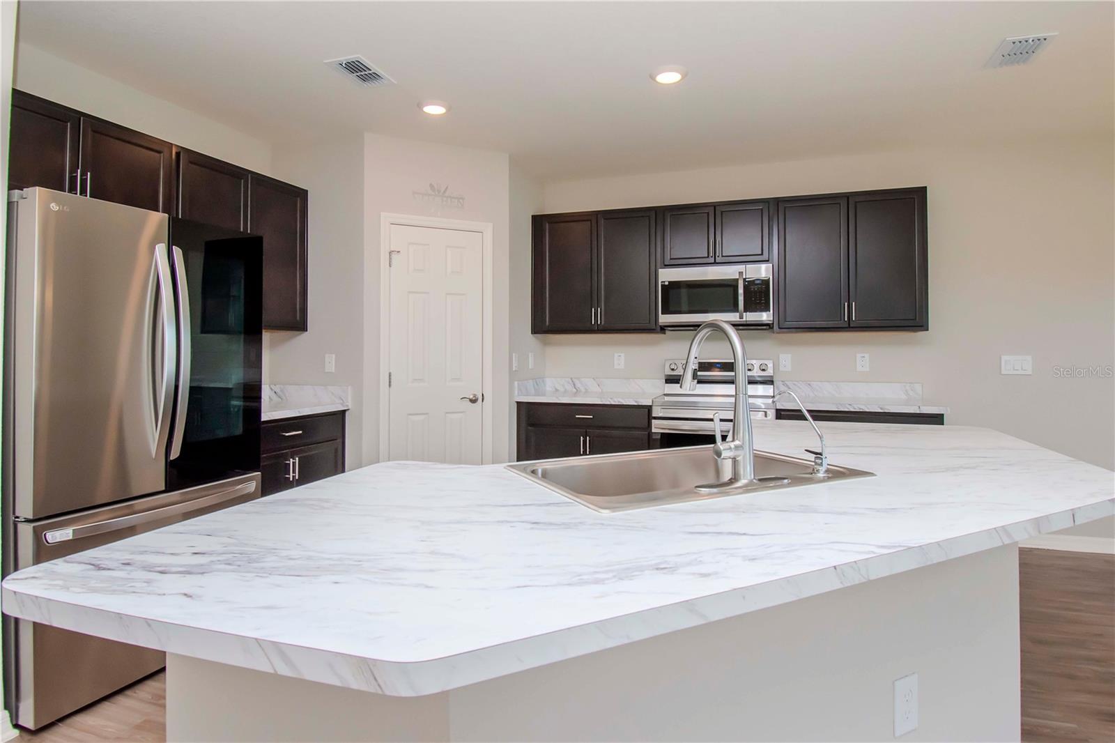 FULLY EQUIPPED KITCHEN WITH BREAKFAST BAR, STAINLESS STEEL APPLIANCES, AND WALK-IN PANTRY